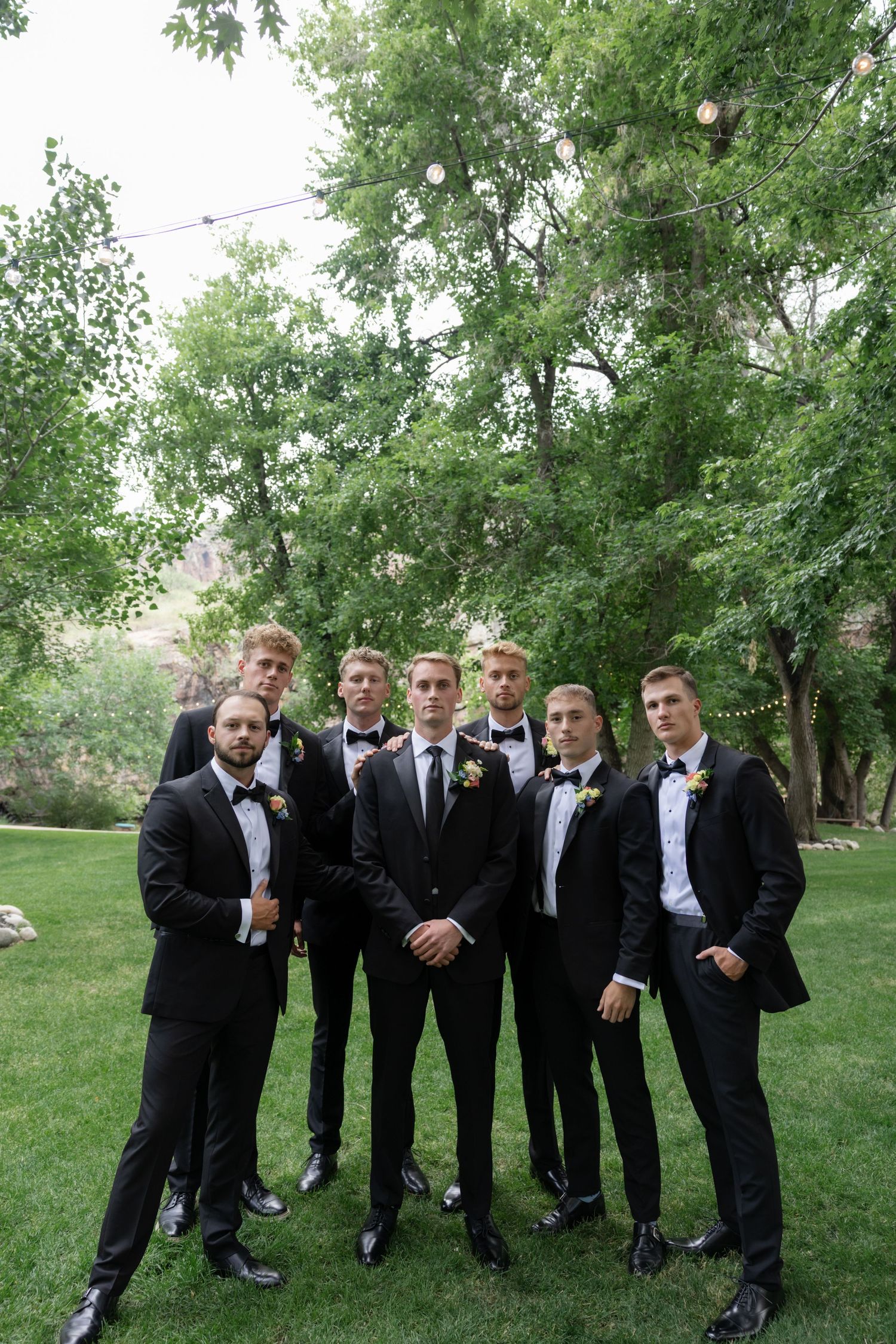 Groomsmen and bridesmaids celebrating joyfully in an outdoor garden setting.