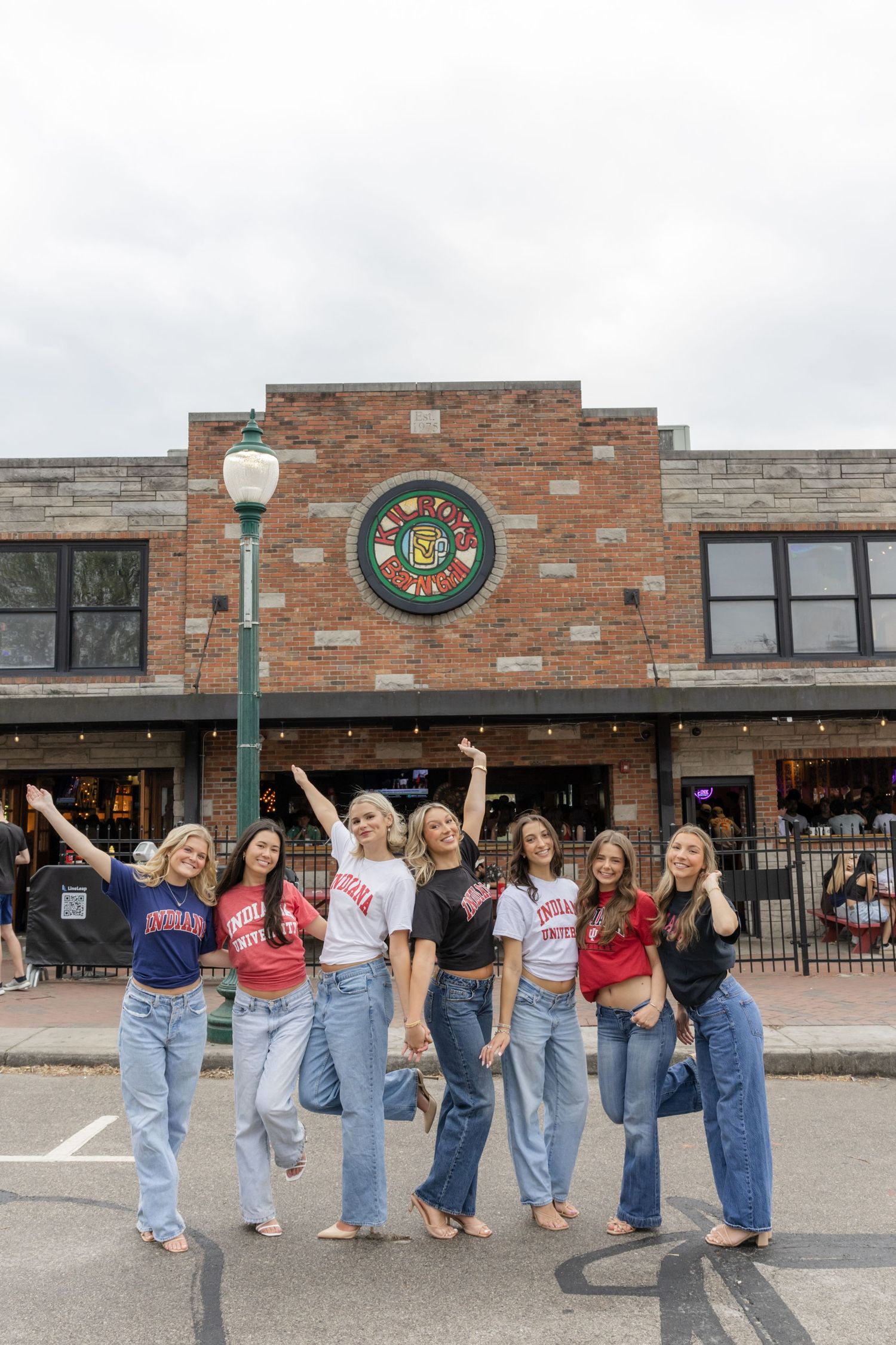 Students in matching denim jeans pose together outside a brick campus building.