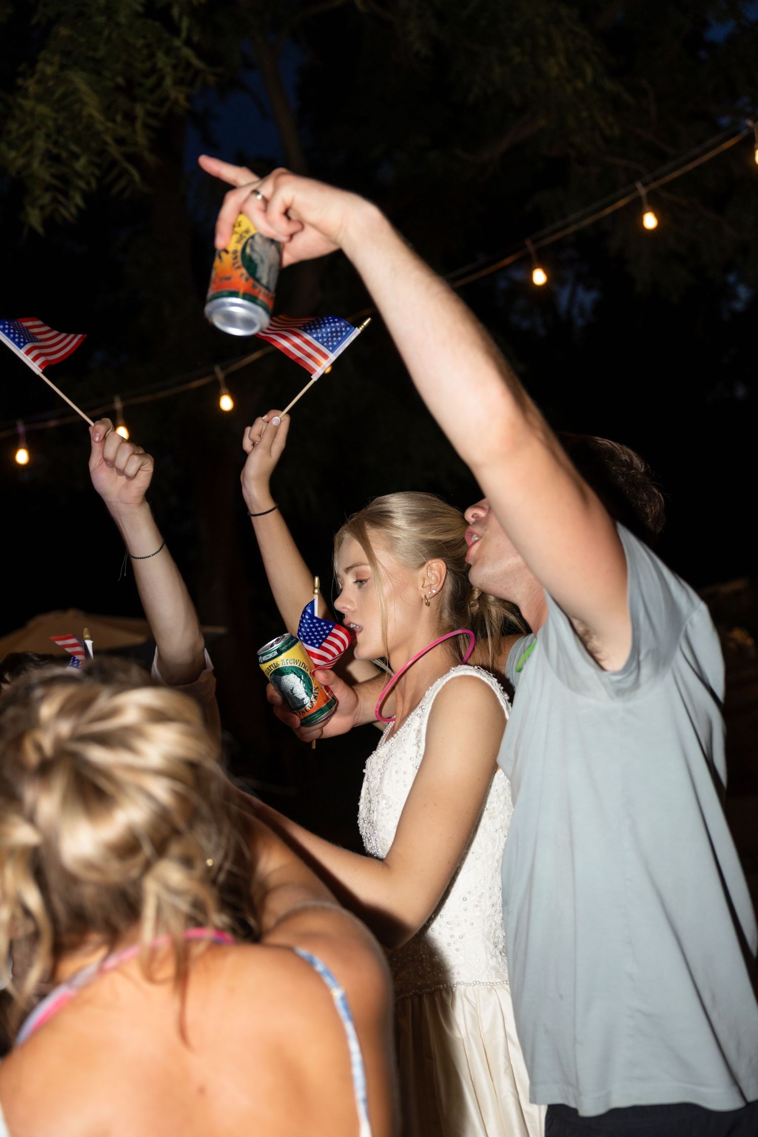 People dancing and raising American flags during an outdoor evening party.