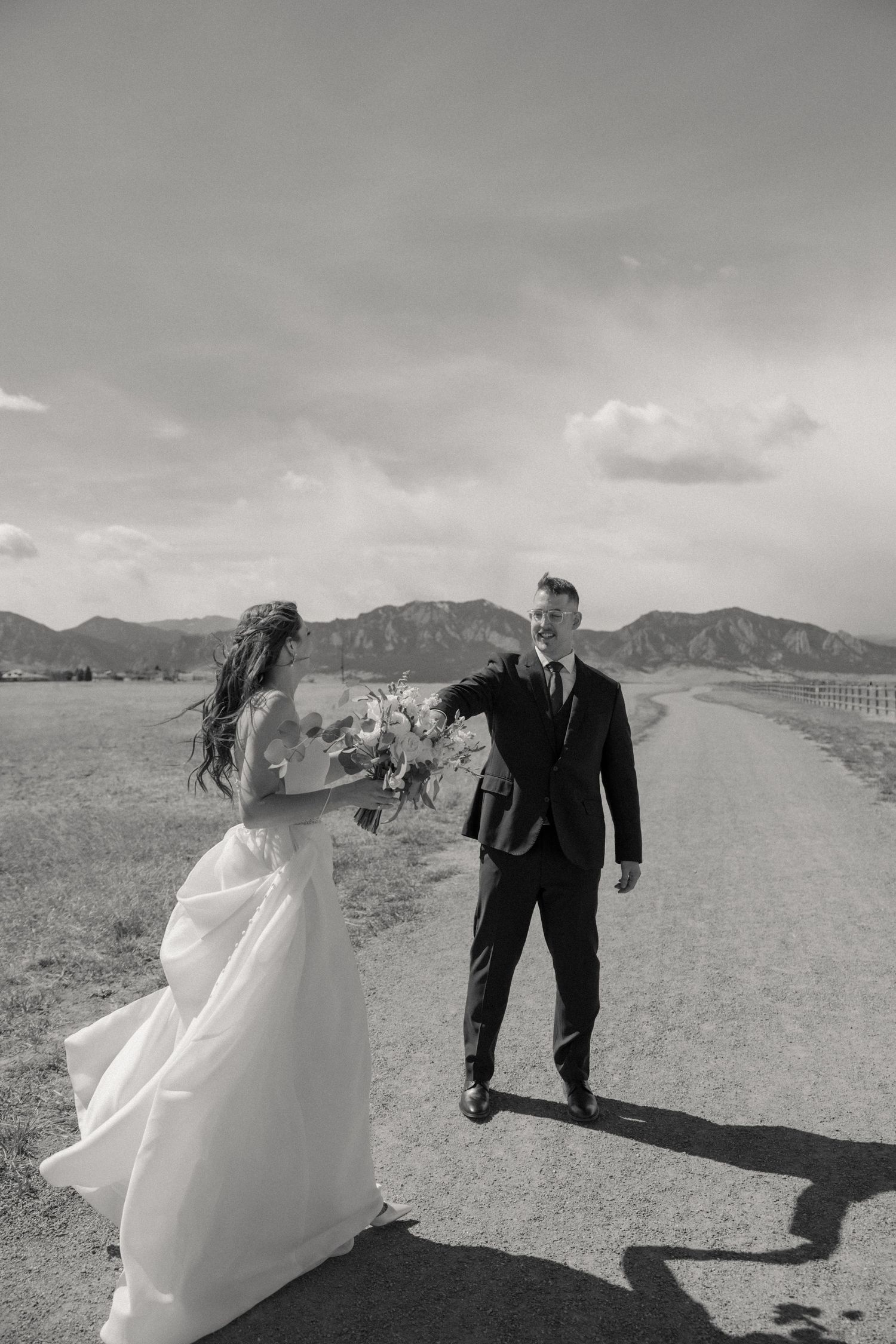 A series of artistic black and white wedding photos showing a couple posing in a desert landscape with mountains.