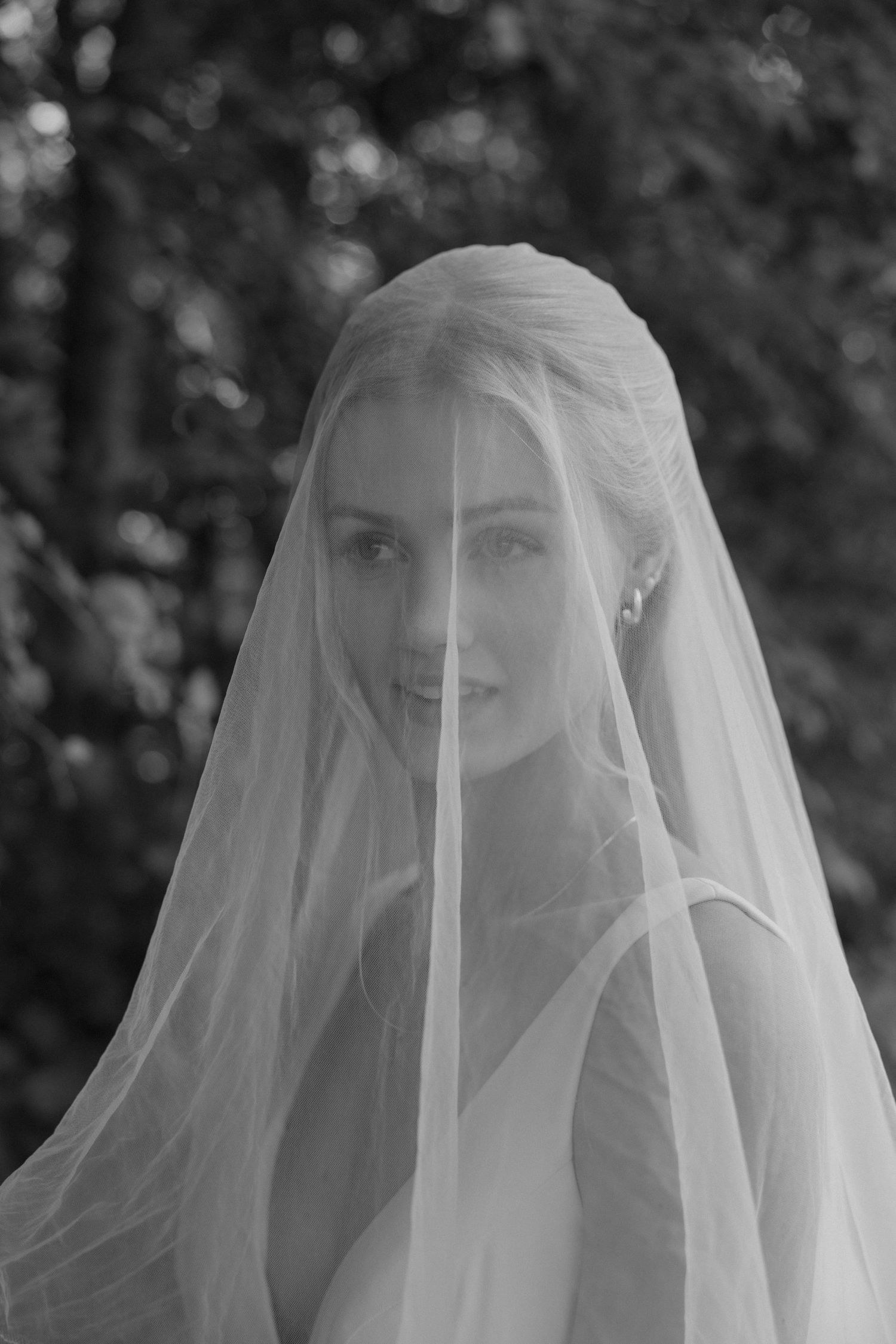 Artistic black and white portrait through a wedding veil's delicate fabric.
