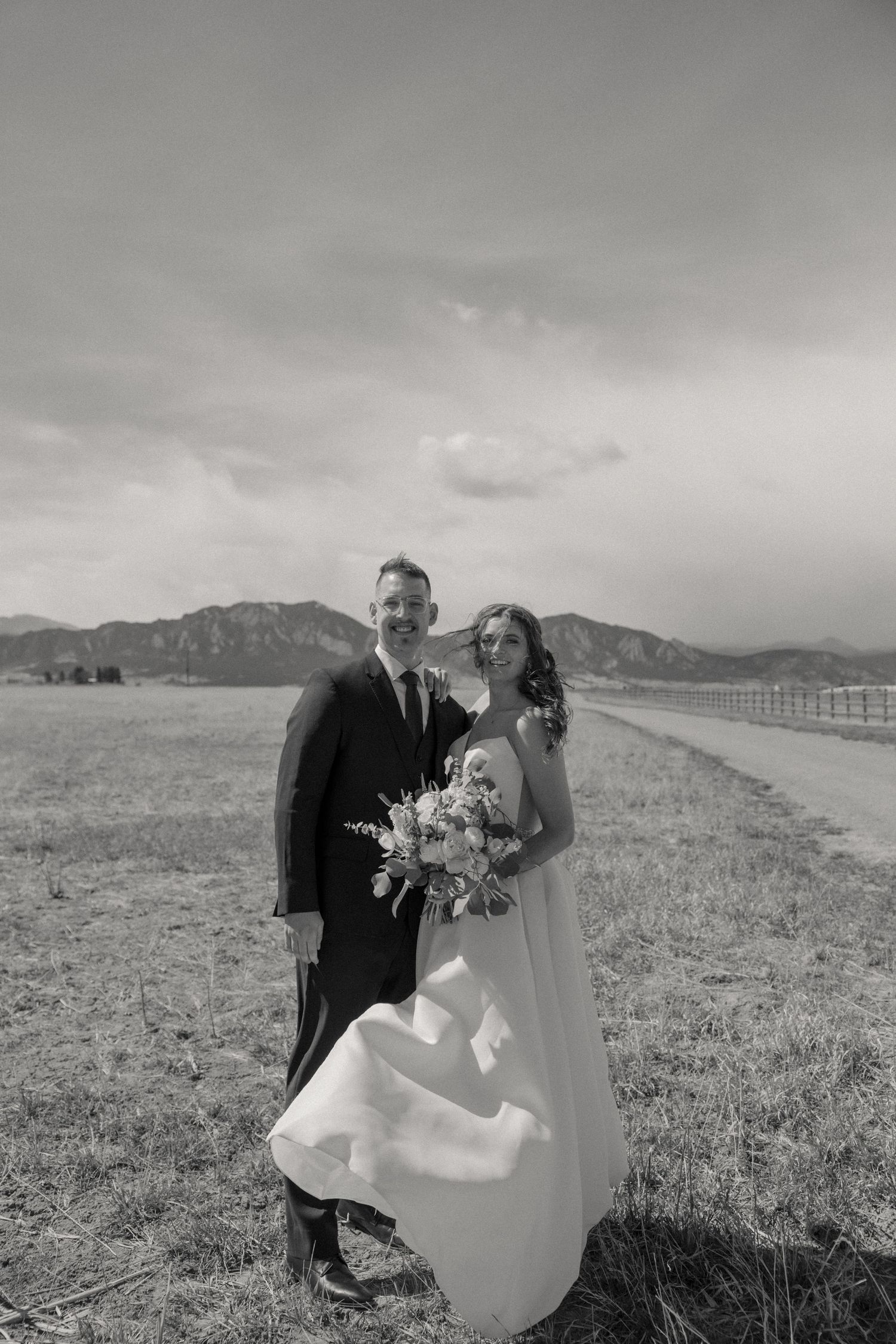 Black and white wedding portrait with mountain landscape in background.