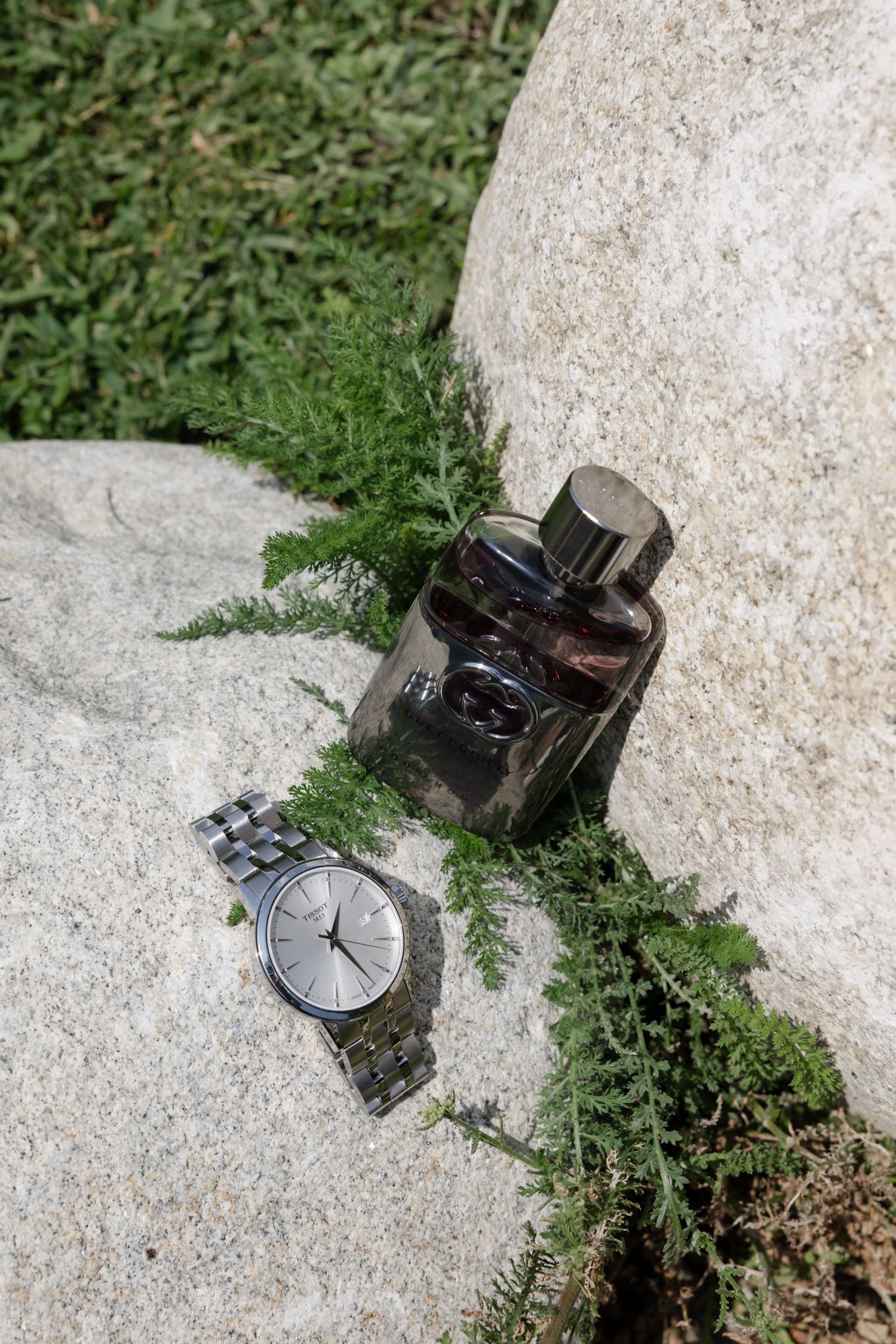 A luxury wristwatch placed artistically on a stone surface with grass in the background.
