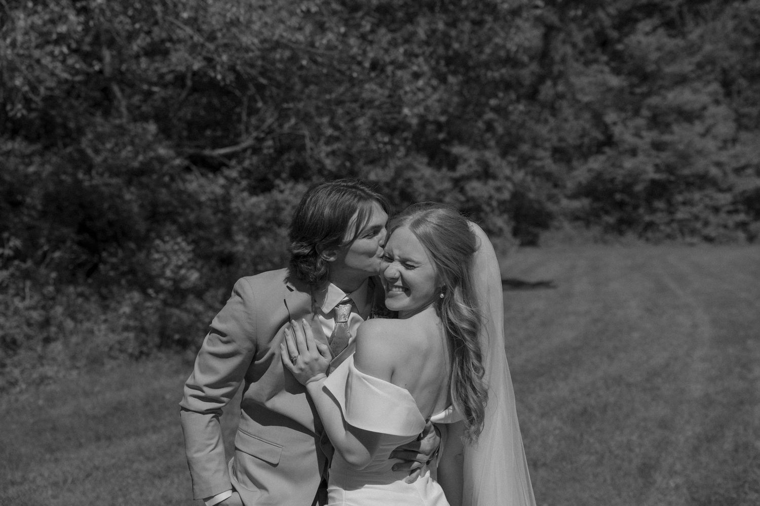 Romantic wedding couple embraces in outdoor garden setting.