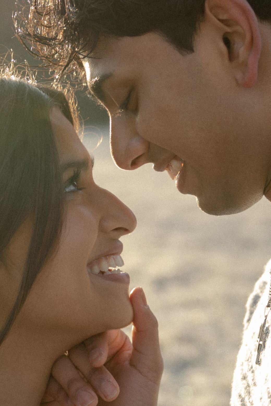 Two people share an intimate close-up moment against a warm sunlit background.