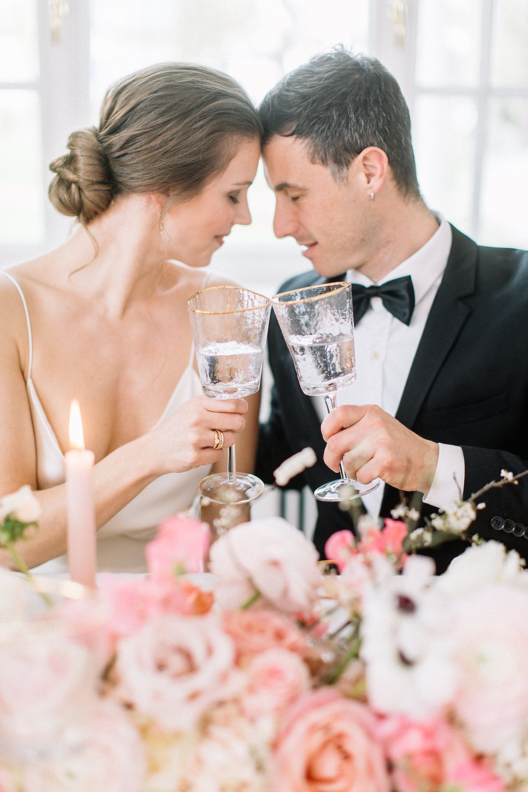 Romantischer Moment mit Champagnergläsern unter rosa Blumendekorationen bei einem eleganten Empfang