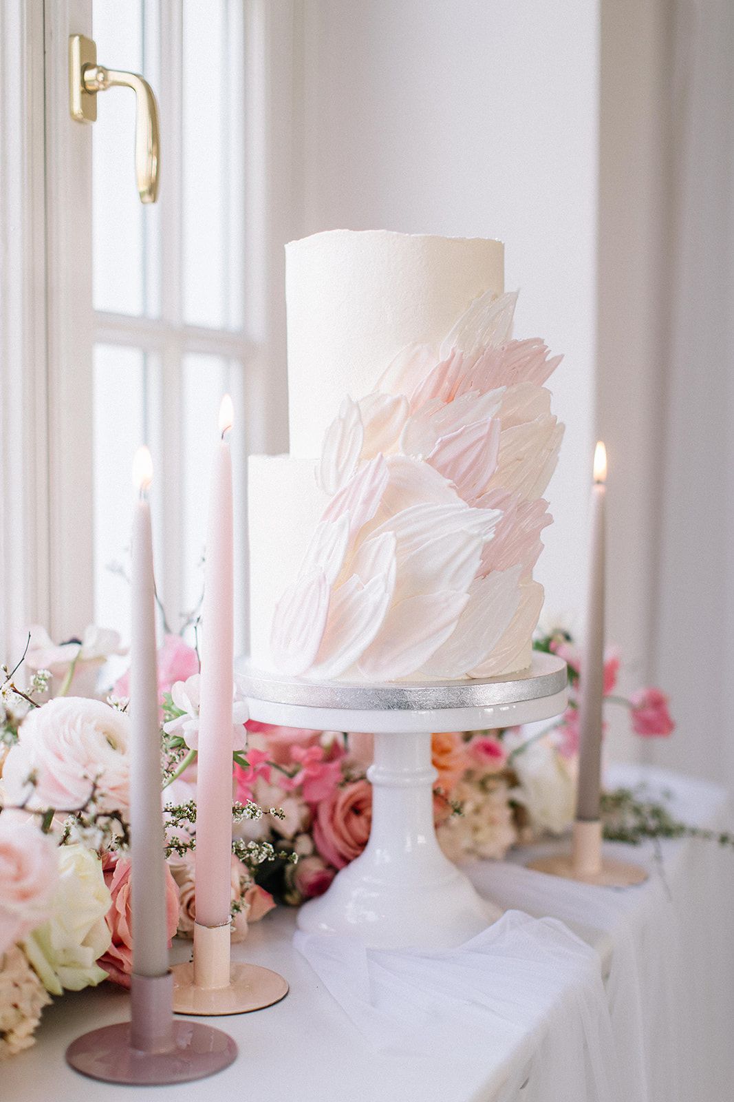 Elegante weiße Hochzeitstorte mit rosafarbenen Pinselstrich Details, präsentiert auf einem Sockel mit rosa Blumendekoration