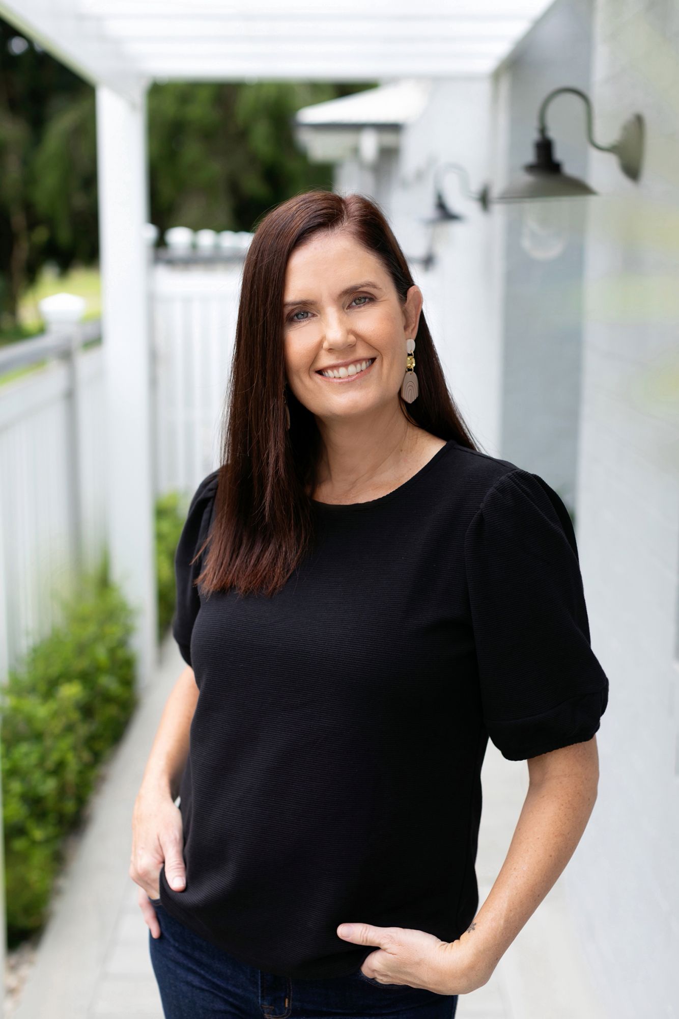Brisbane Cleveland business photographer show casing business woman in black top posing against white outdoor columns.