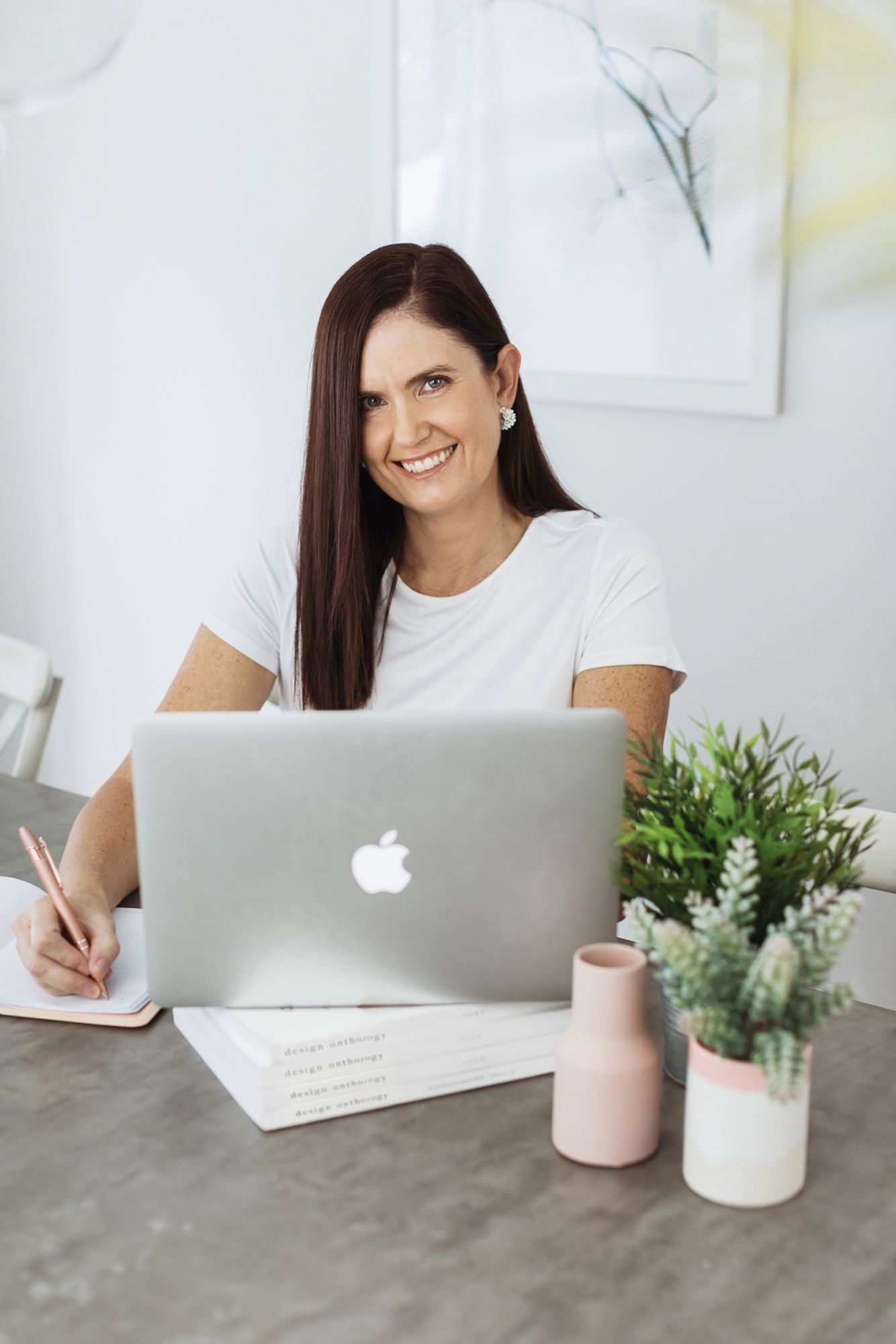 Professional business woman at modern desk with MacBook laptop in bright Brisbane office setting for her business photo shoot.