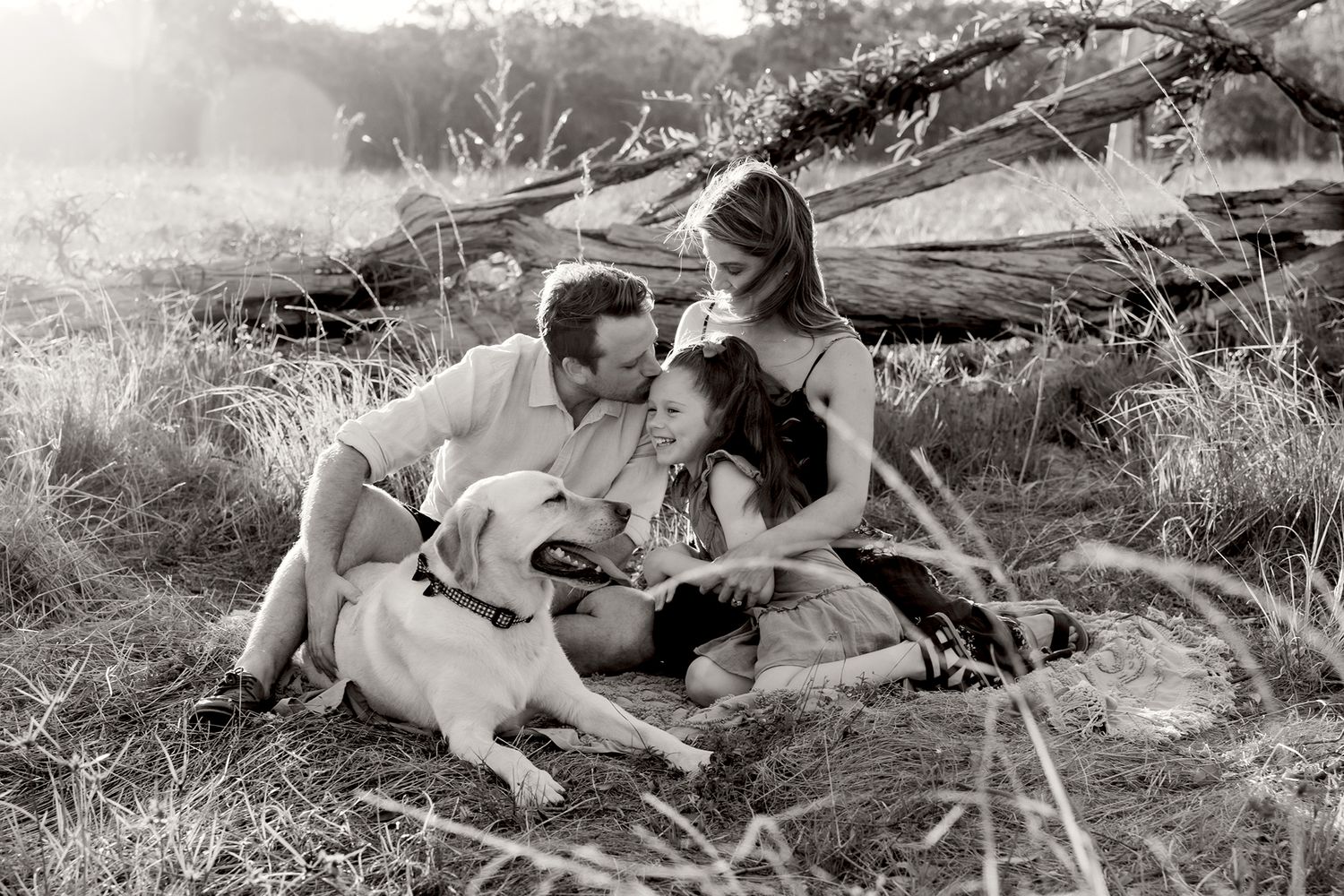 Brisbane family photographer captures family with their dog in grassy field.