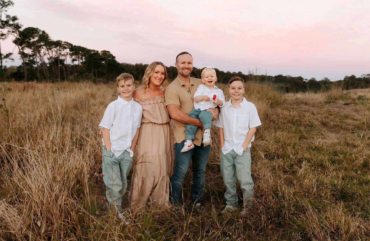 Family photoshoot in a rustic grassy field setting during golden hour at Mt Cotton Brisbane.