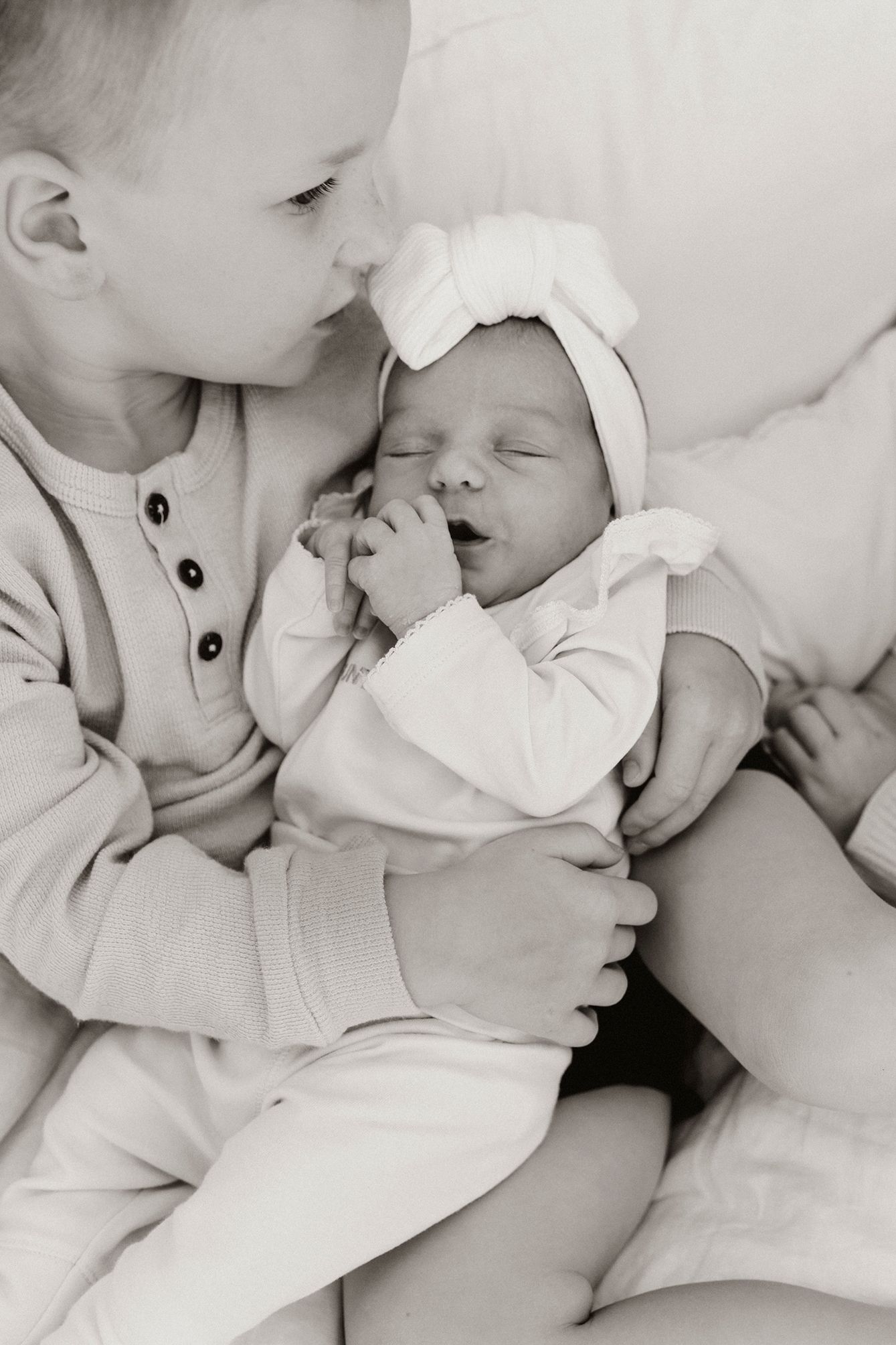 Black and white sibling photography capturing newborn connection in Brisbane.