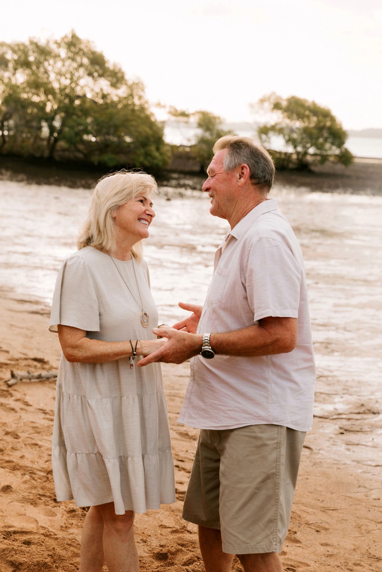 A senior couple shares a tender moment while walking along the sandy beach of Wellington Point, Brisbane.