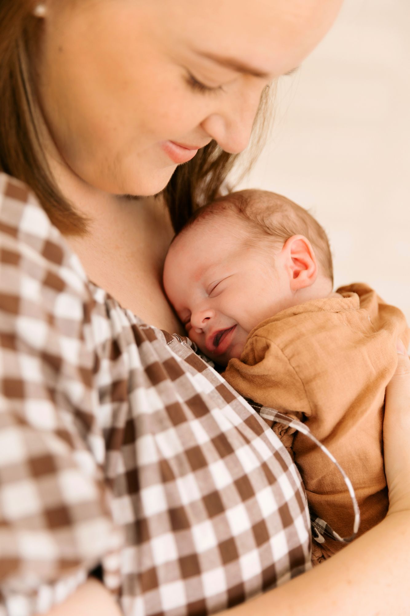 A new Brisbane mother tenderly holds her sleeping newborn baby at home. Brisbane in-home newborn photography.