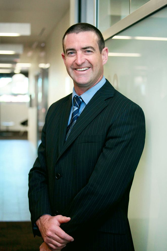 Brisbane corporate photographer illustrating a professional in pinstripe suit standing in modern office hallway.
