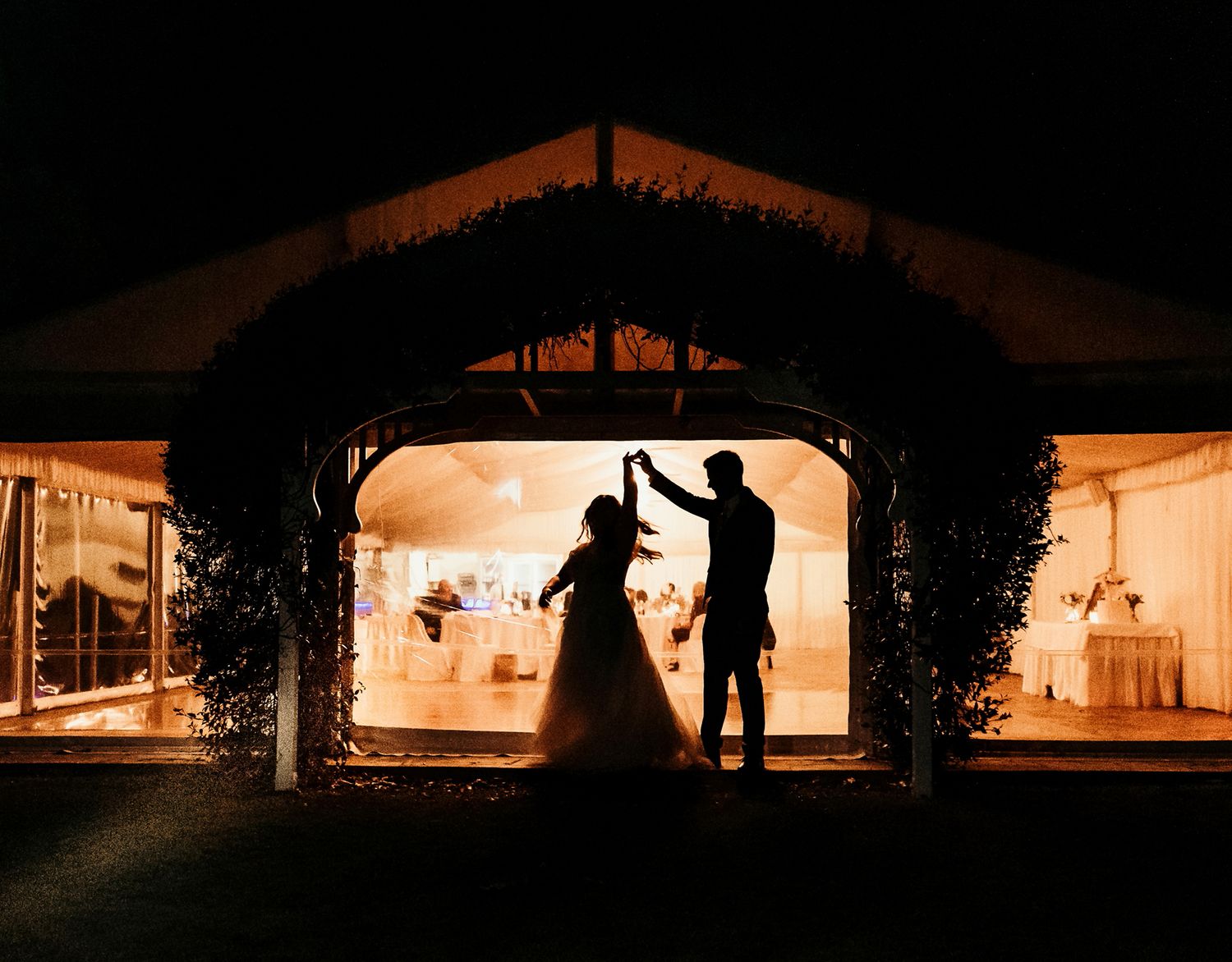 Brisbane wedding photography of bride and groom silhouette dancing against a dark evening sky creating a dramatic panoramic skyline view.