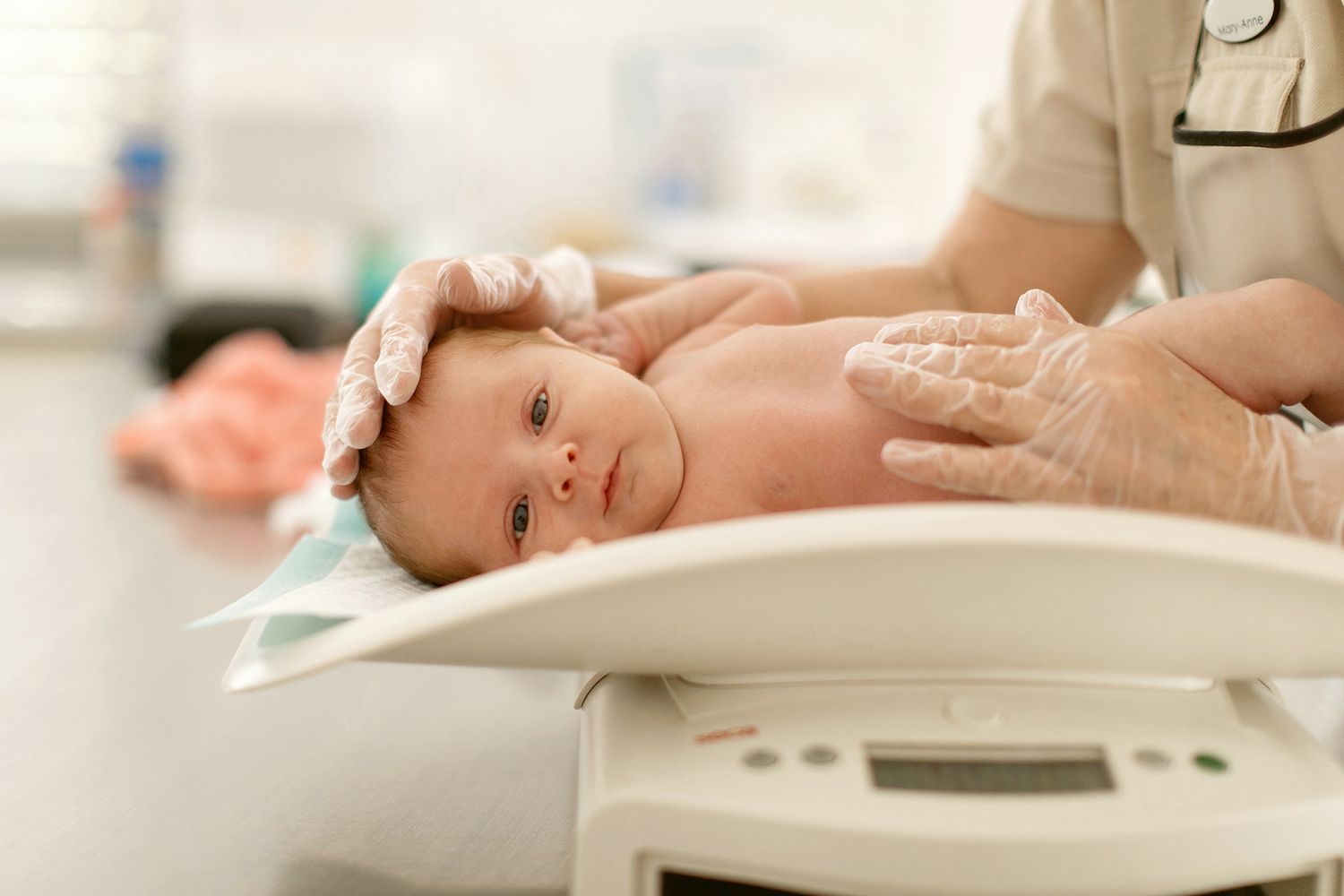 Brisbane business photography illustrating health care professional weighing newborn baby on medical scale.