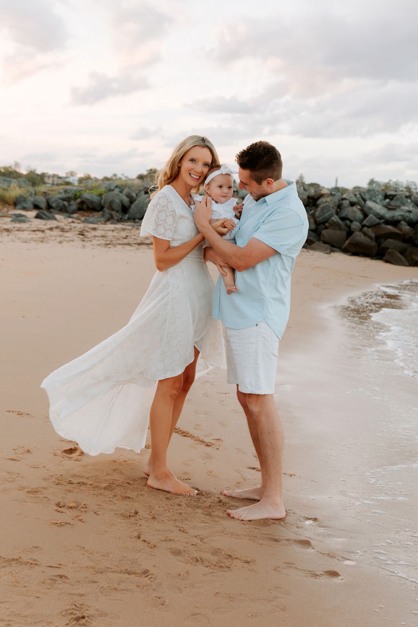 Family beach photoshoot playing in the sand near rocky shoreline at Gold Coast.