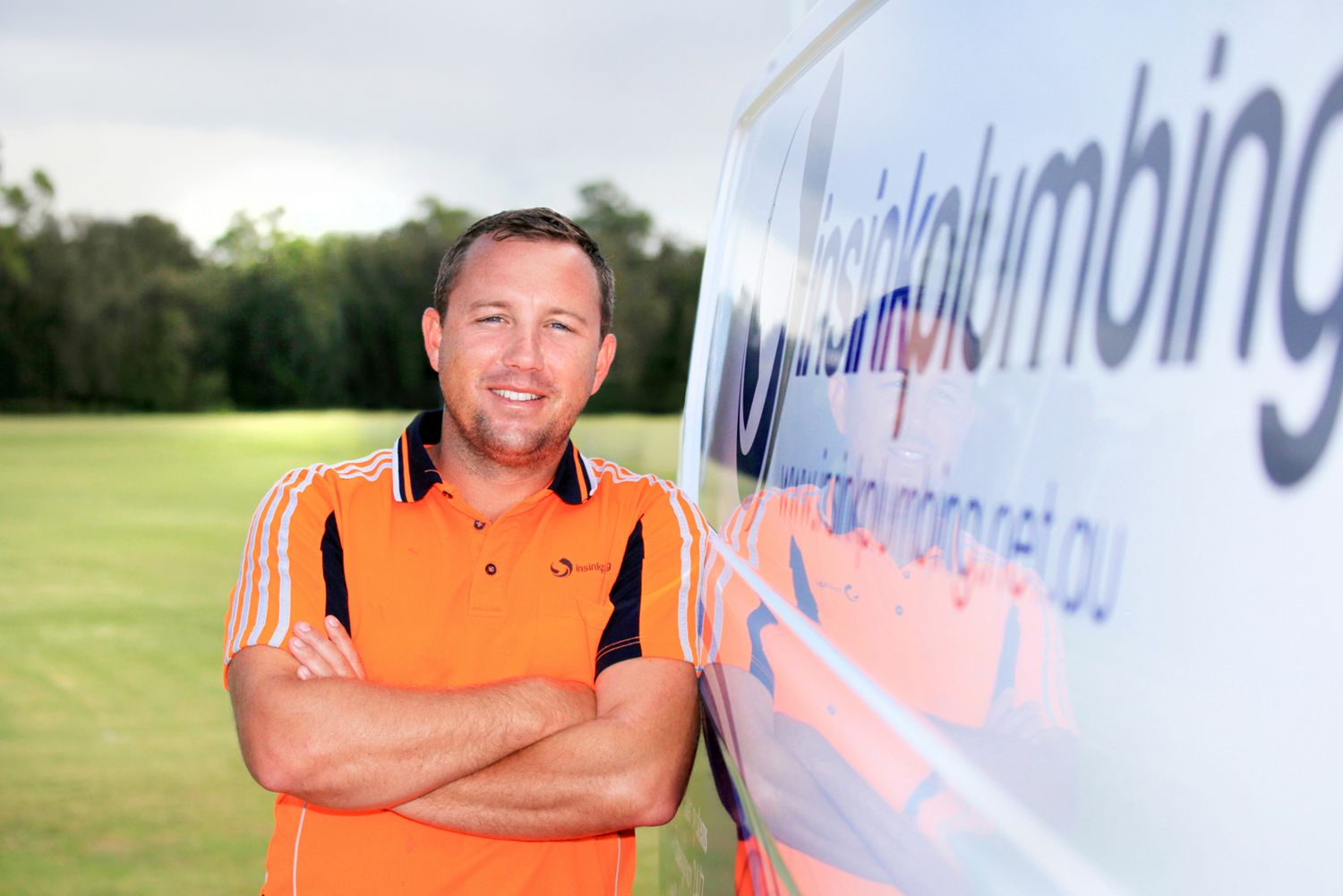 A tradesman smiles while posing next to his work vehicle in the Brisbane suburb of Capalaba for his business photography.