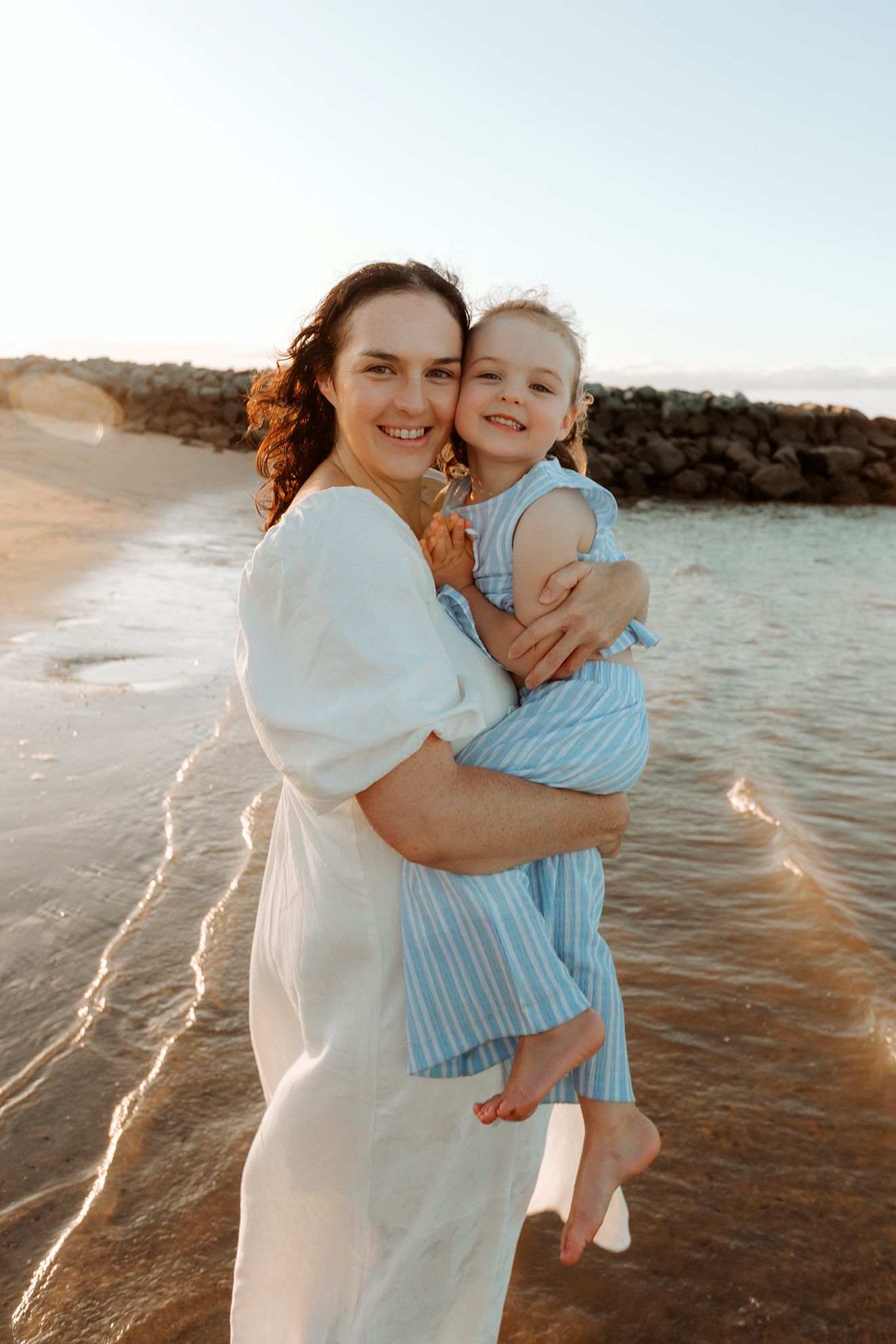 Tender beach mother and daughter portrait with soft lighting featuring the rocky coastline of Brisbane bayside suburb of Raby Bay.