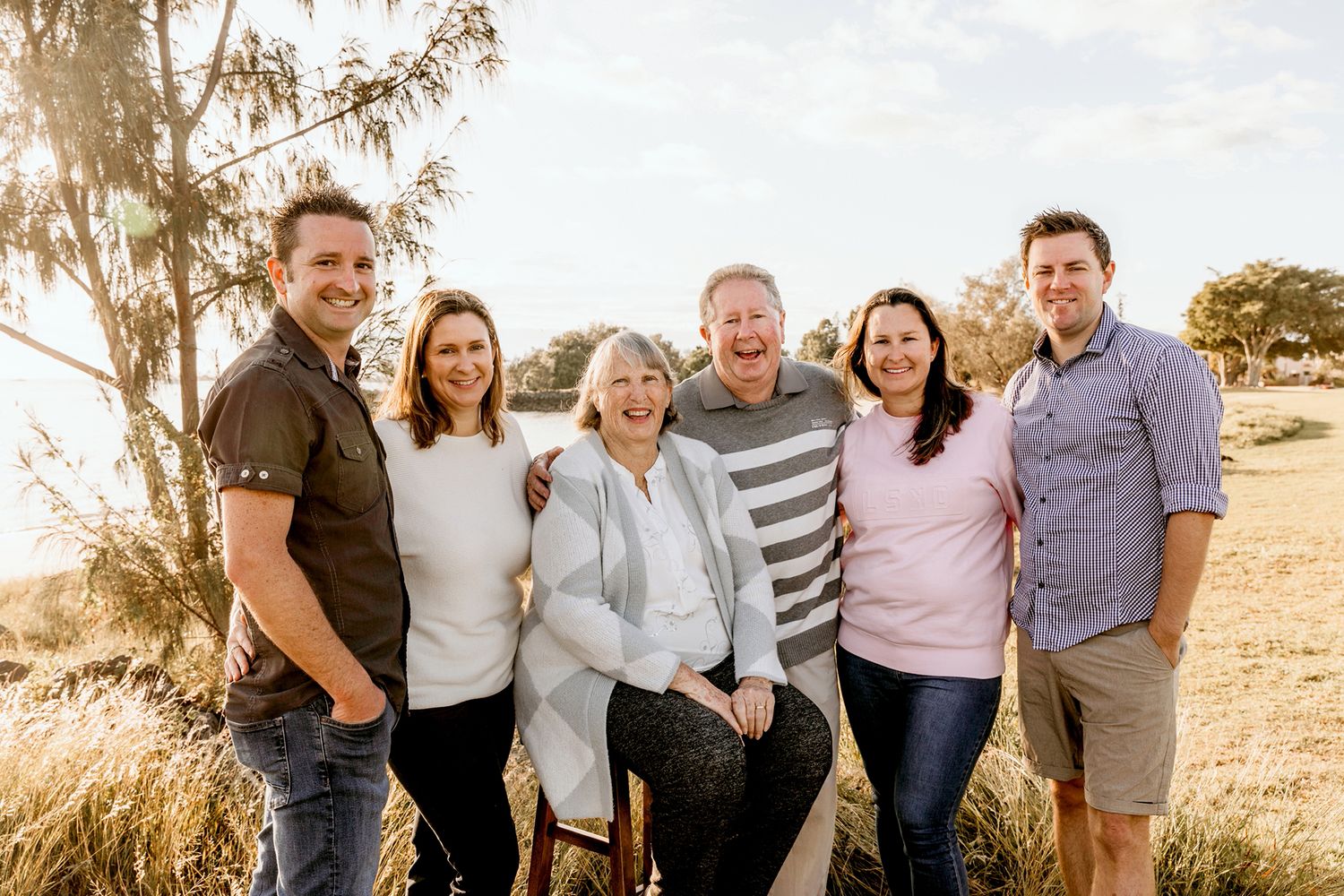 An extended family gather outside for a photo shoot during golden hour in a natural setting at the Brisbane bayside suburb of Raby Bay.