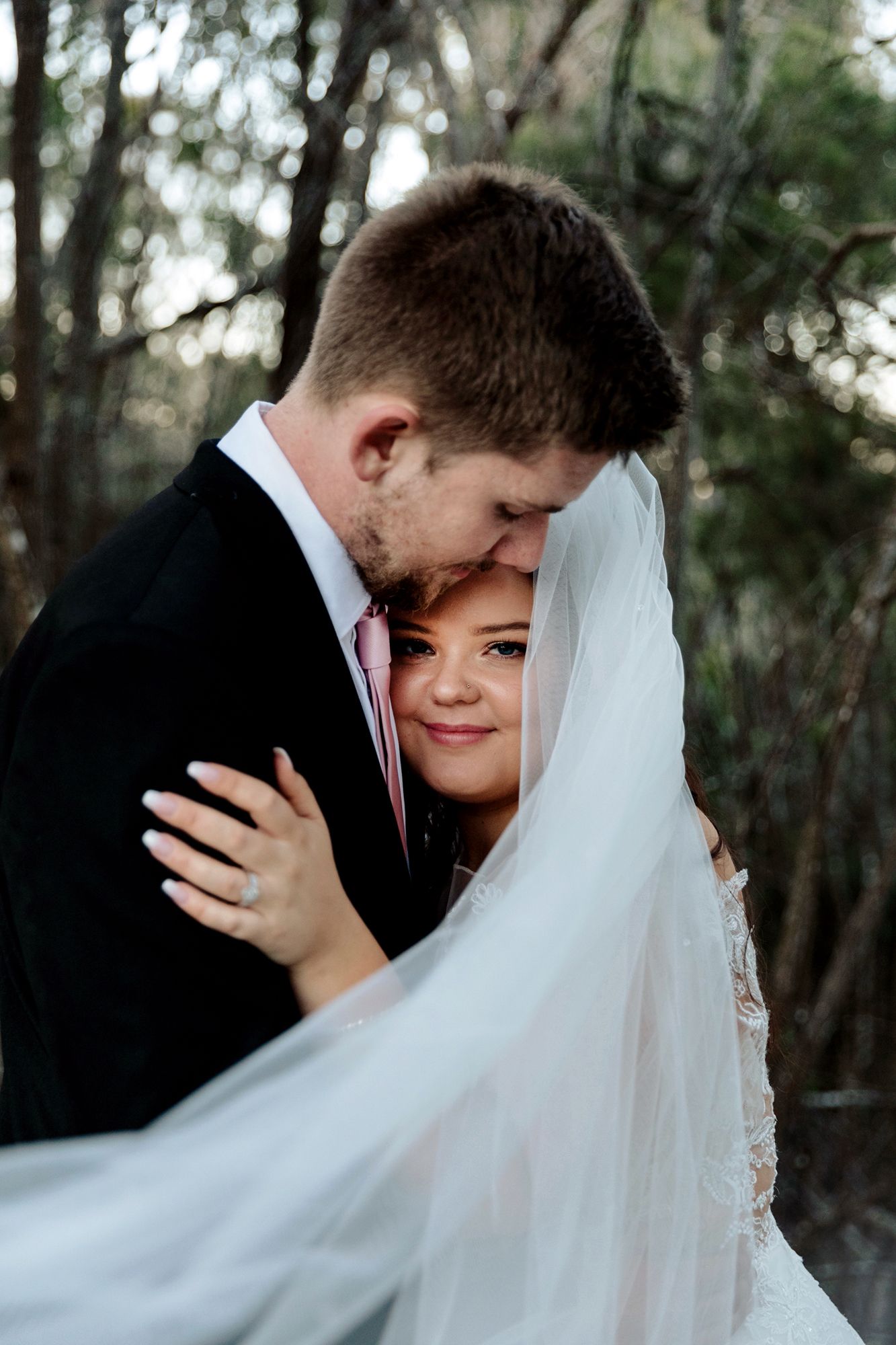 Intimate wedding portrait showing tender moment between newlyweds with flowing veil by Brisbane wedding photographer, Jot Studio.