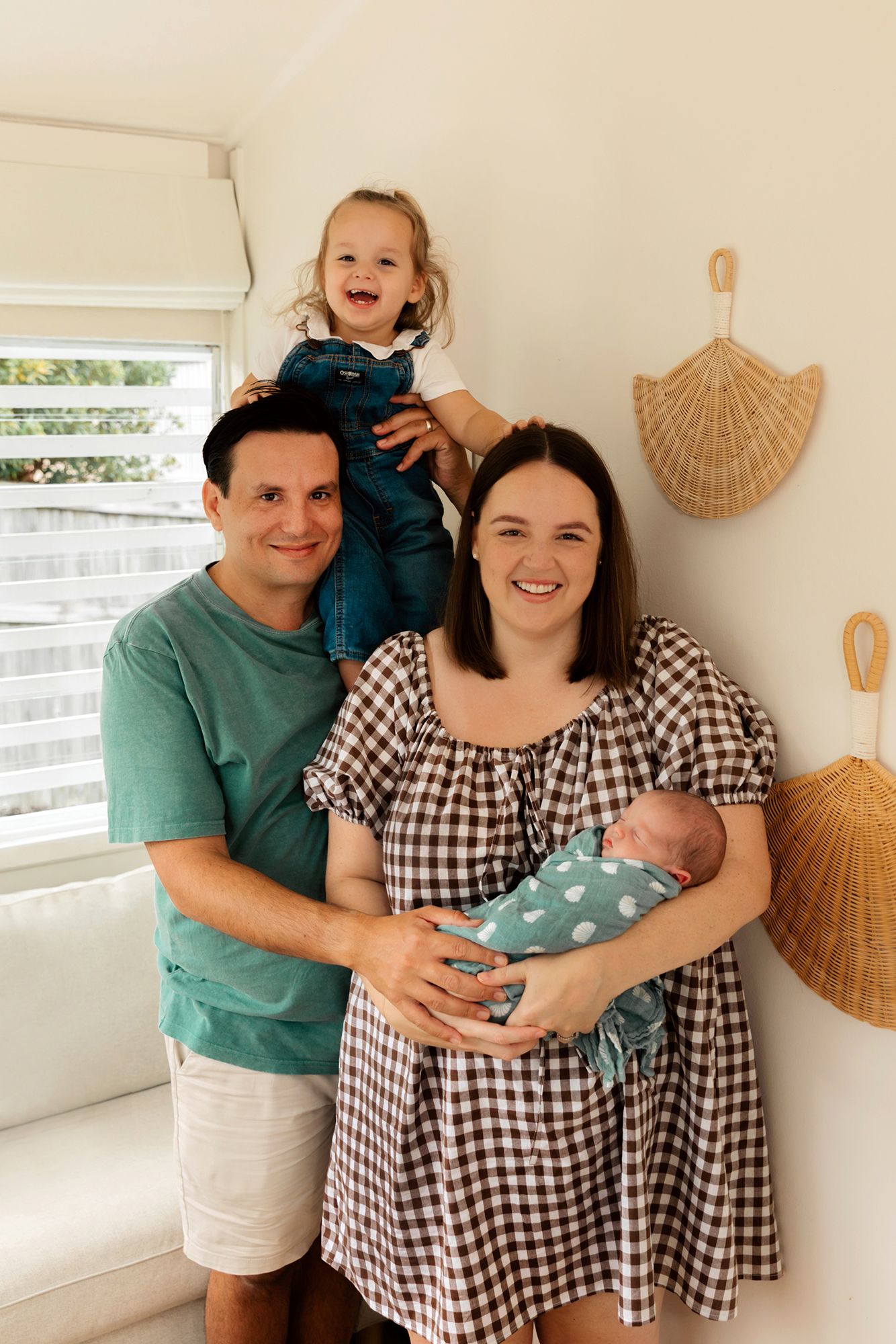 Happy family with newborn baby in their bright cozy home setting pose for family professional photography in Brisbane.