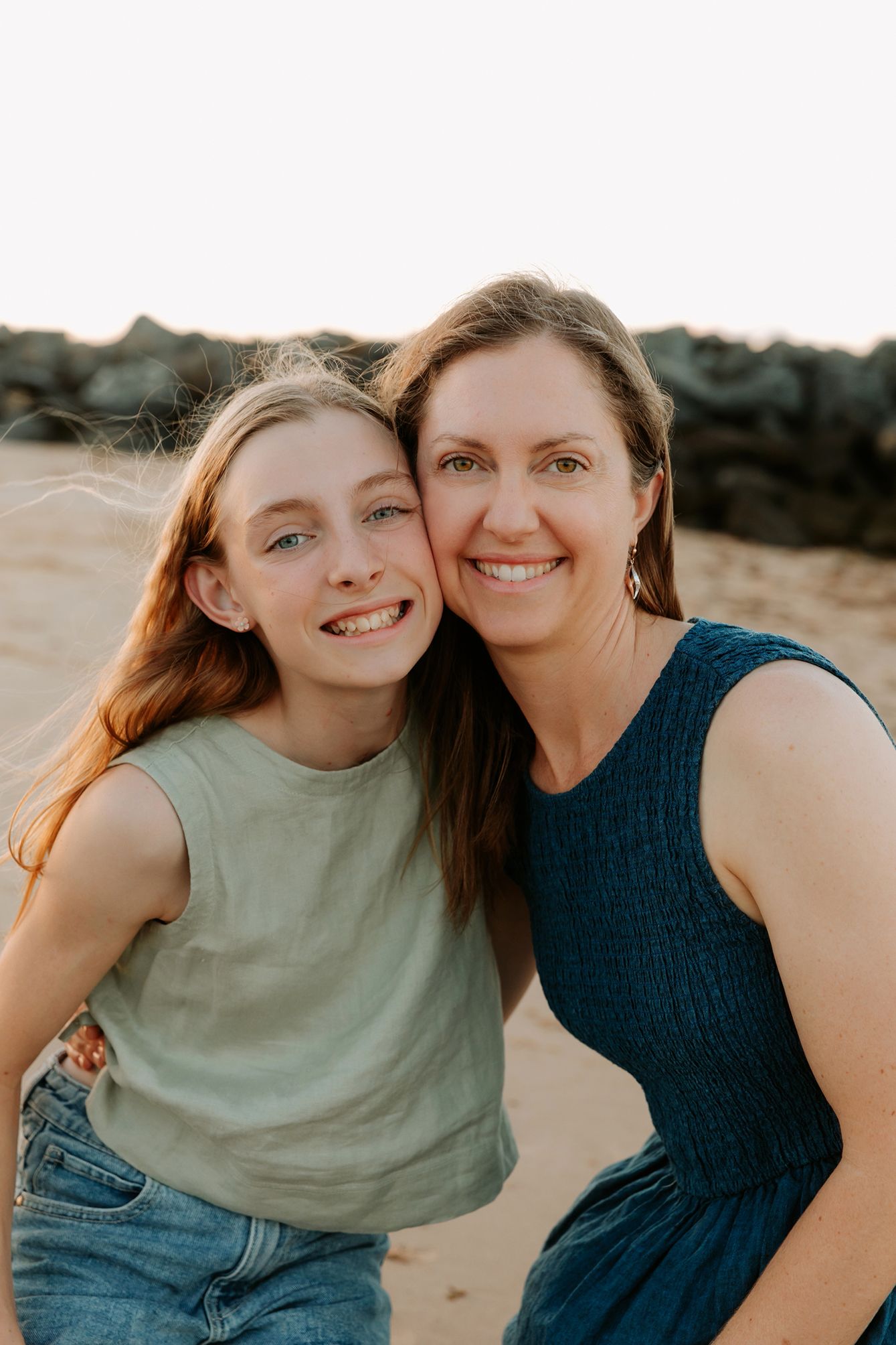 Brisbane family photography on beach during golden hour showing closeness between mother and daughter.