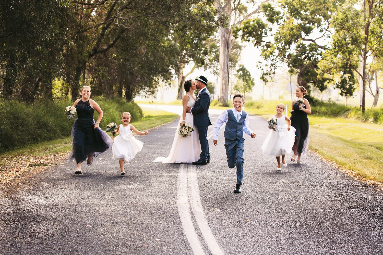 Fun bridal party running on street in Mt Cotton, Brisbane. Wedding photography specialising in the Redlands area.