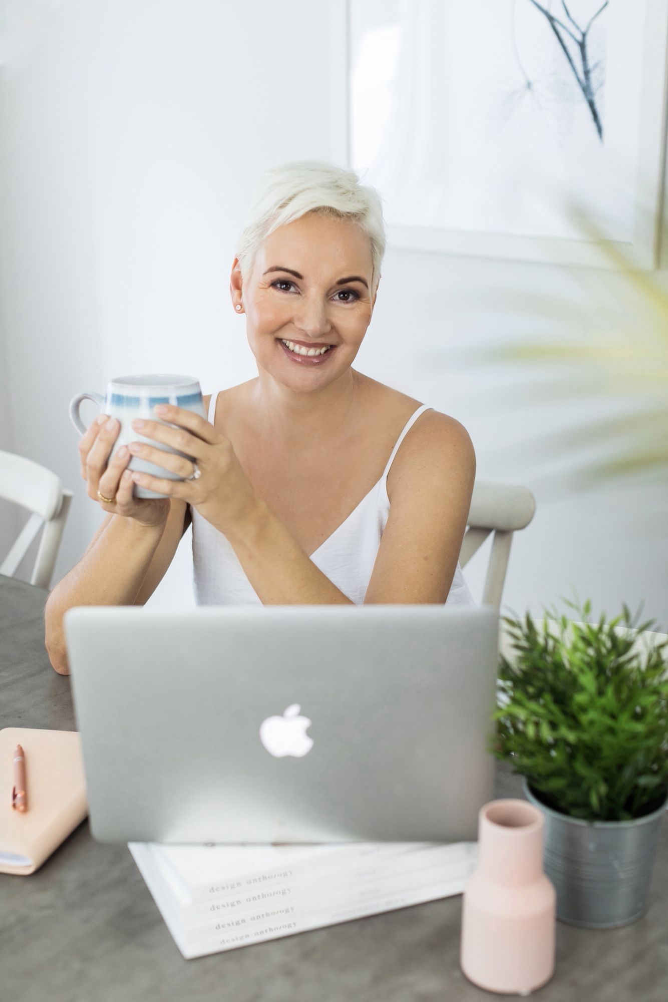 Raby Bay business photographer illustrating a business ownder working on MacBook laptop with plants and coffee mug at desk setting.