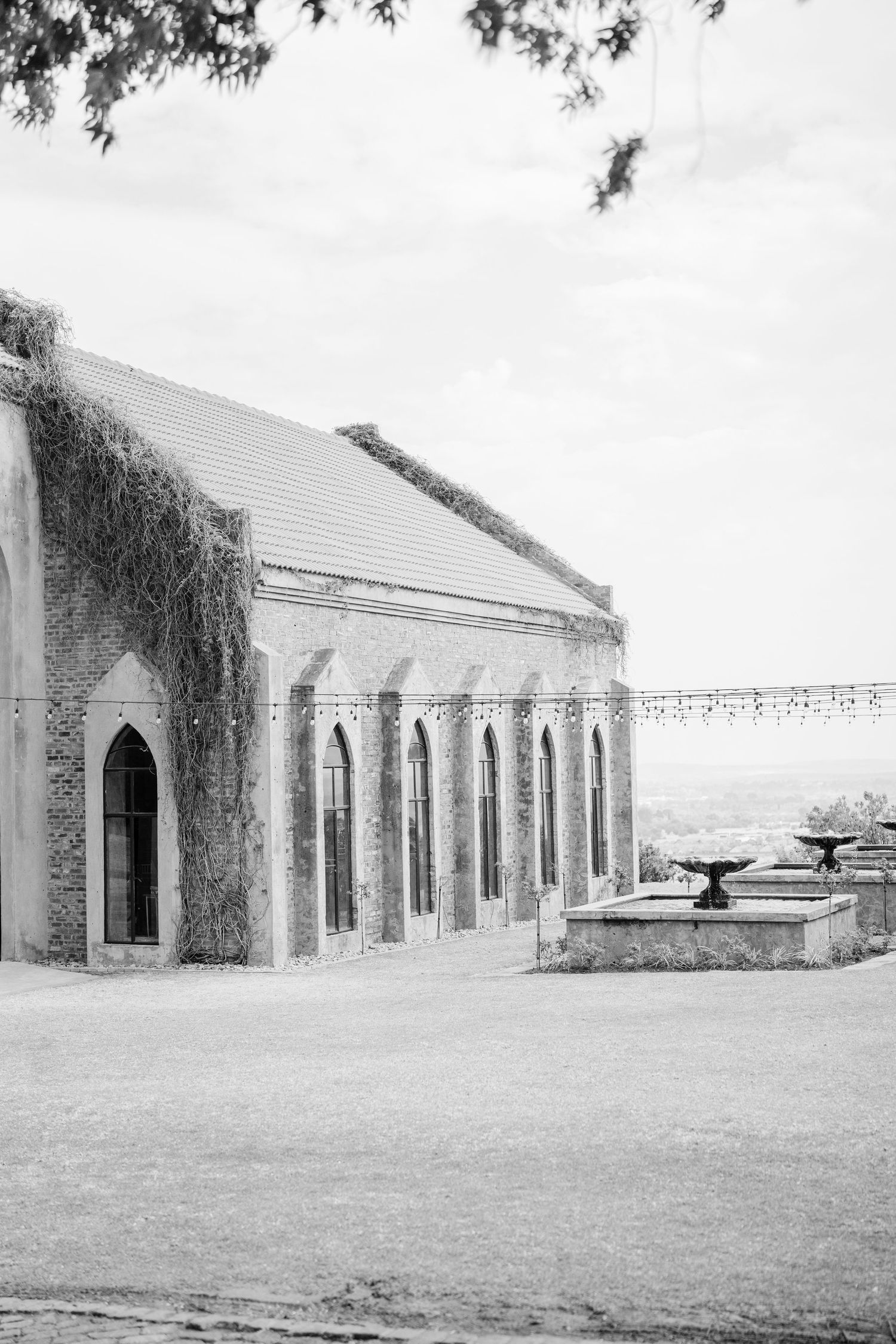 Historic stone building with arched windows and ivy-covered walls overlooking a scenic landscape.