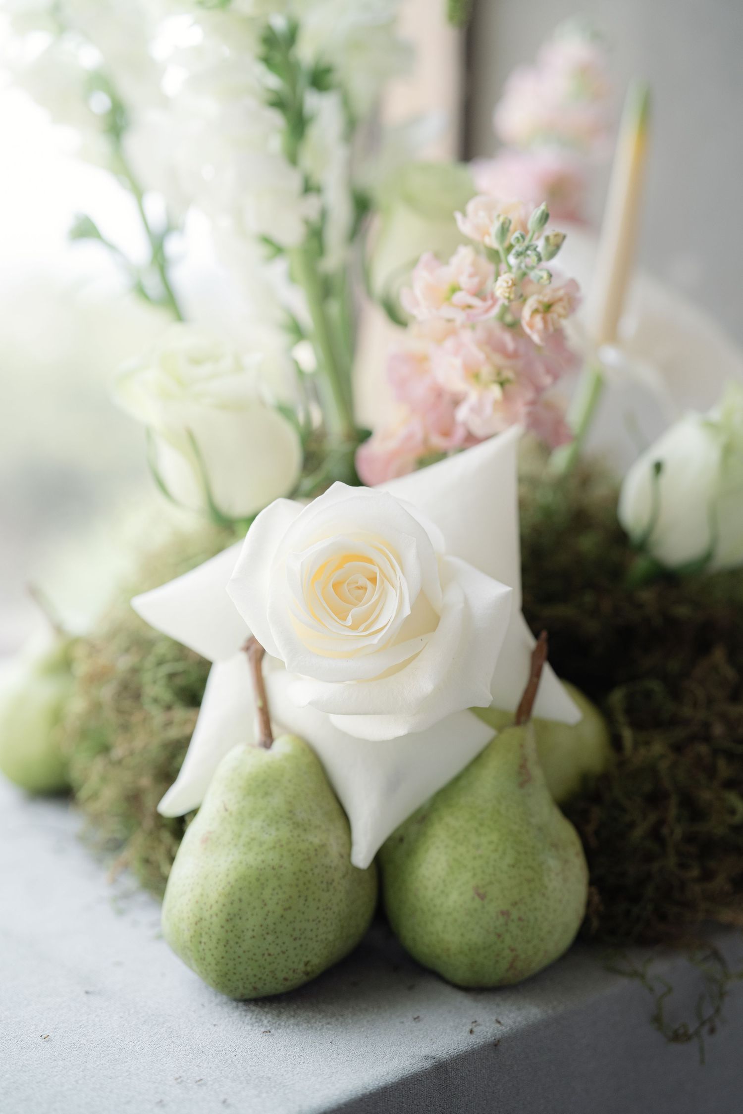 White roses rest delicately atop green pears in an elegant table decoration arrangement.