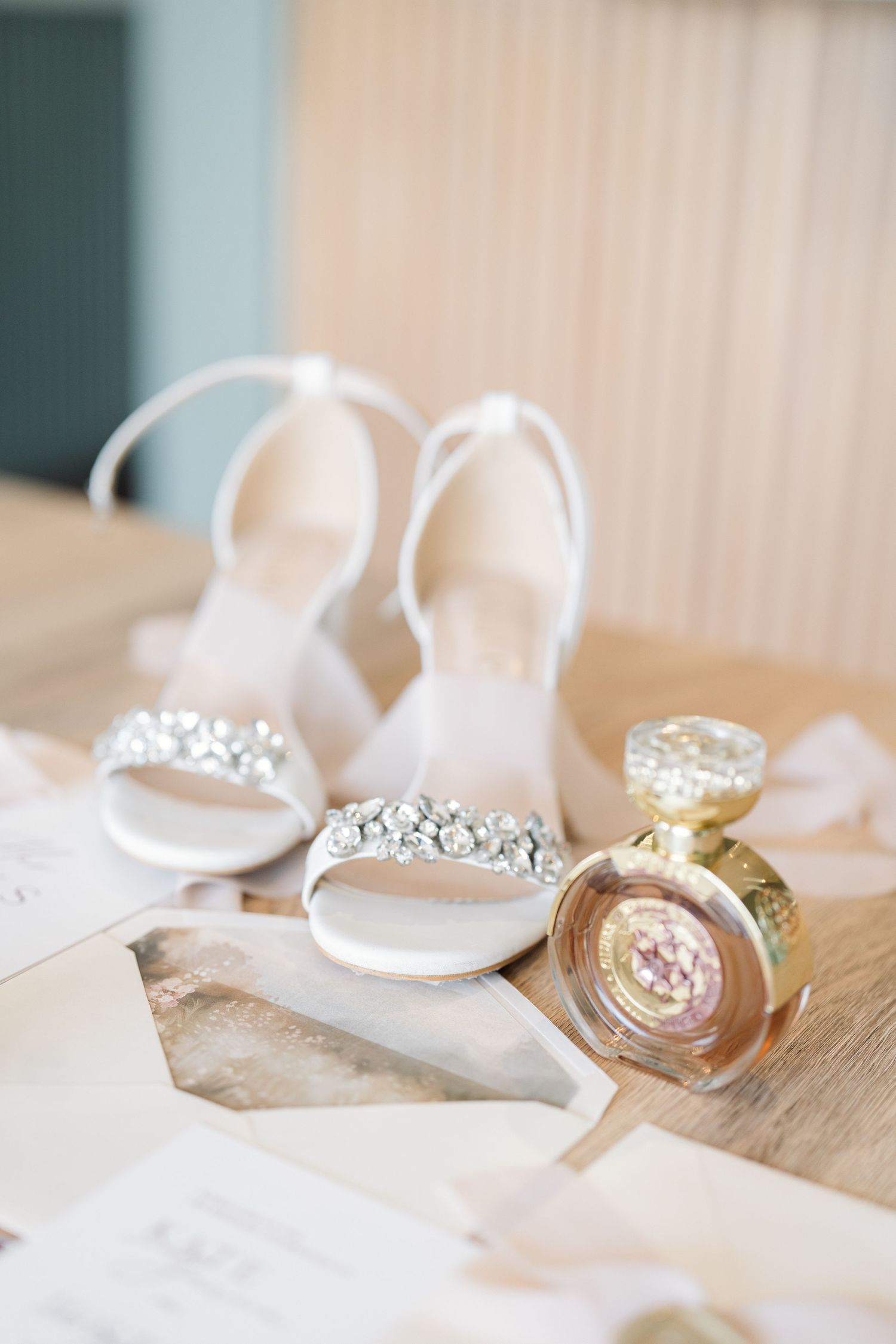 Elegant wedding rings and jewelry arranged on a light wooden surface with soft white fabric.