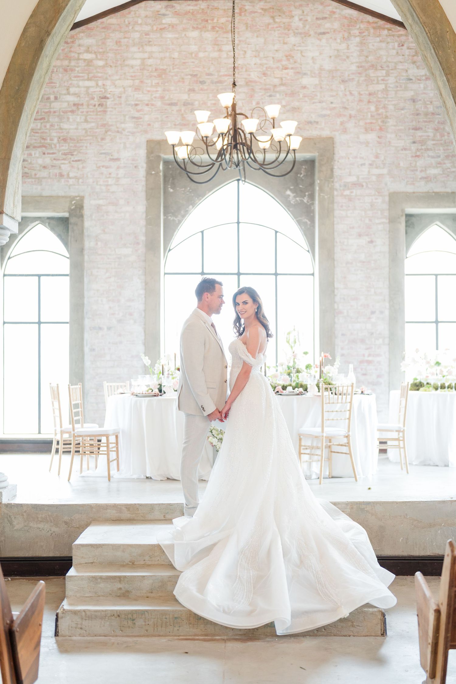 A series of romantic wedding photos showing a couple dancing in an elegant white brick venue with arched windows and chandeliers.