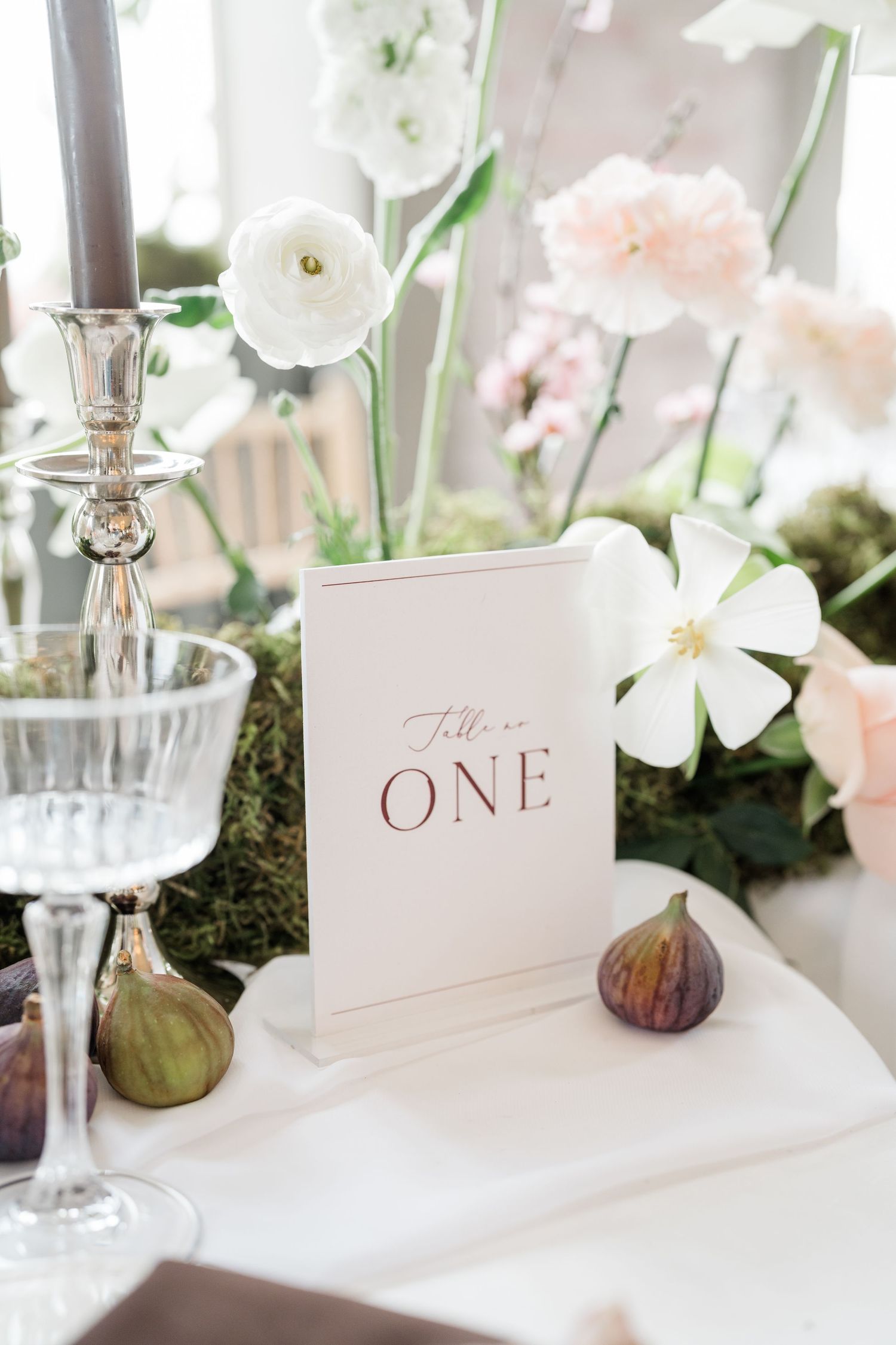 Elegant wedding table setting with delicate white flowers, table numbers and crystal glassware.