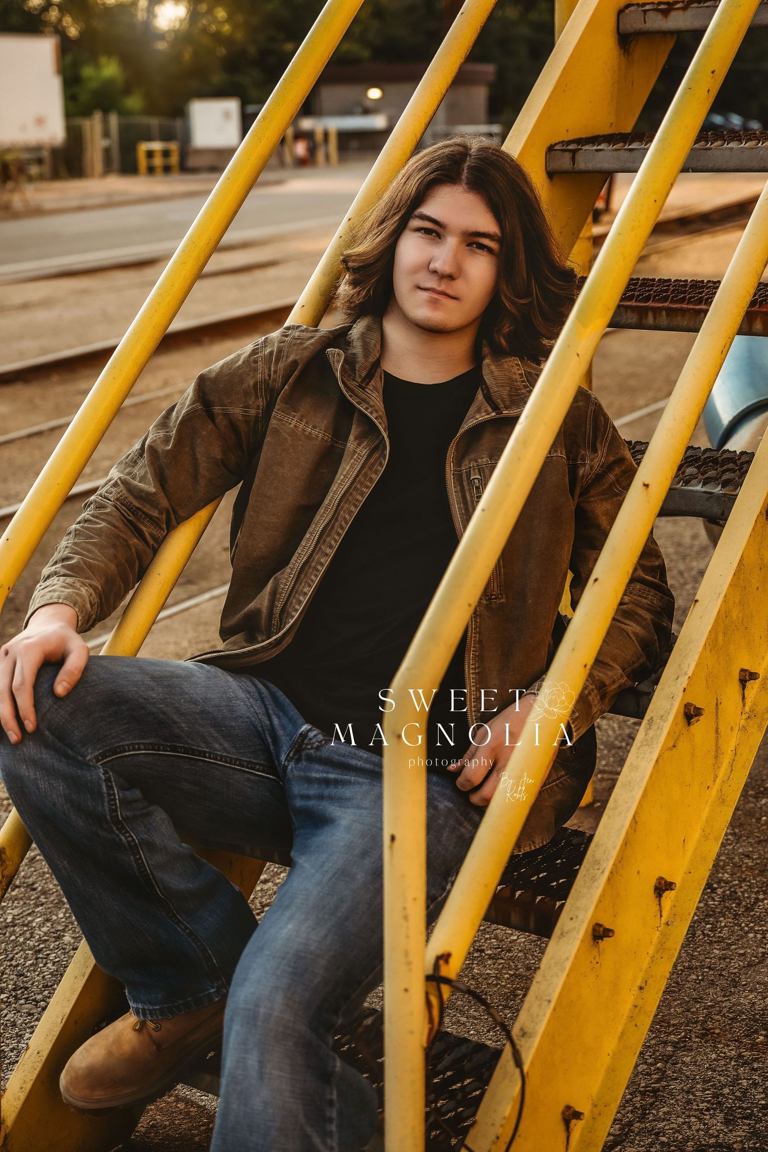 Casual portrait session on yellow metal bleachers wearing leather jacket and jeans.