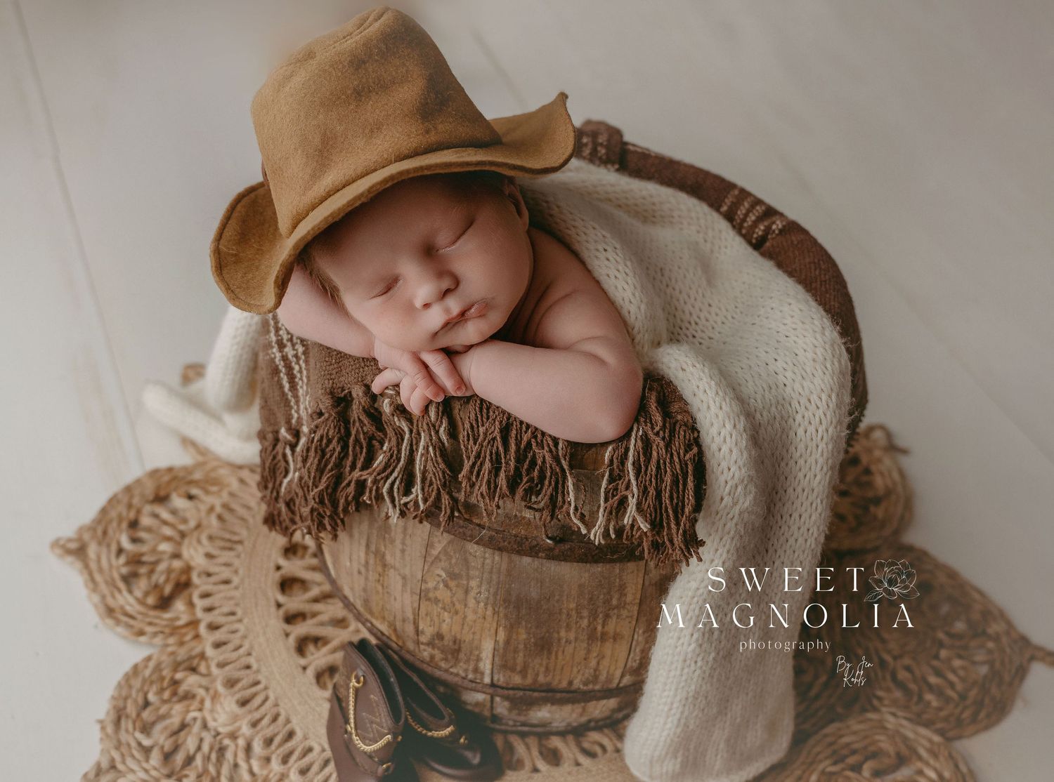 Artistic overhead shot of sleeping newborn on textured tan and cream fabrics.