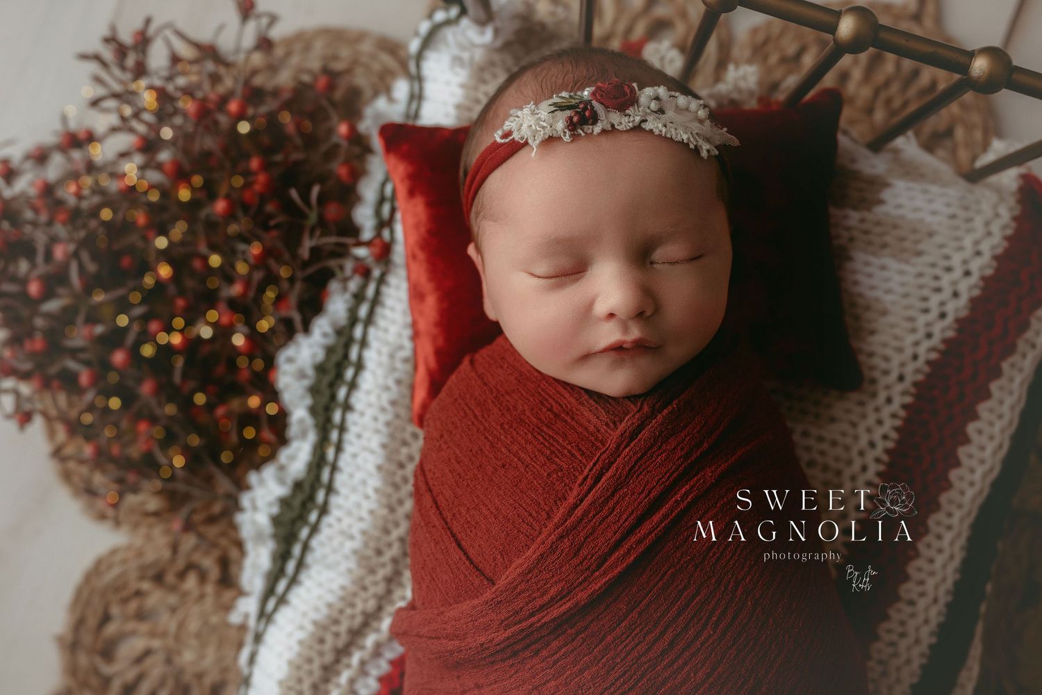 Newborn photography session with rustic red decorations and soft textured blankets in warm autumn tones.