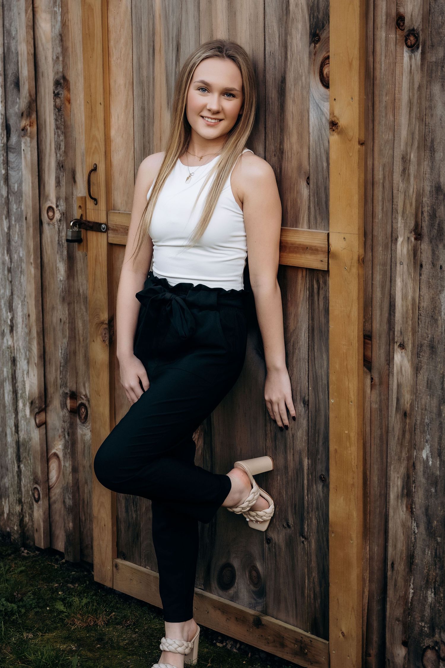 Casual portraits against rustic wooden fence wearing black and white outfit.