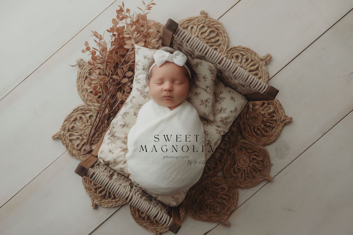 Minimalist newborn photography with soft textures and neutral colors on white wooden backdrop.
