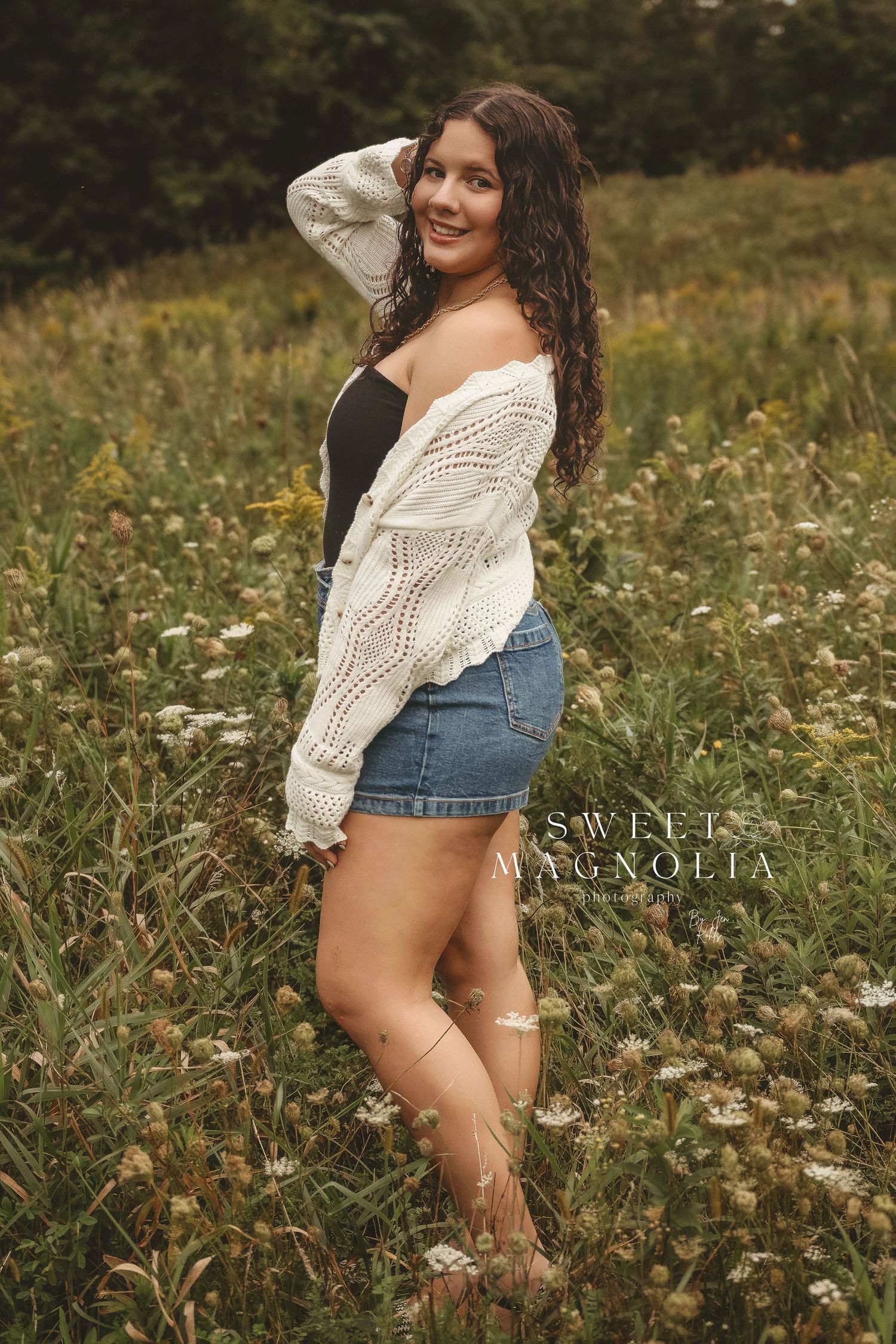 Summer portrait session in wildflower field with white sweater and denim shorts.