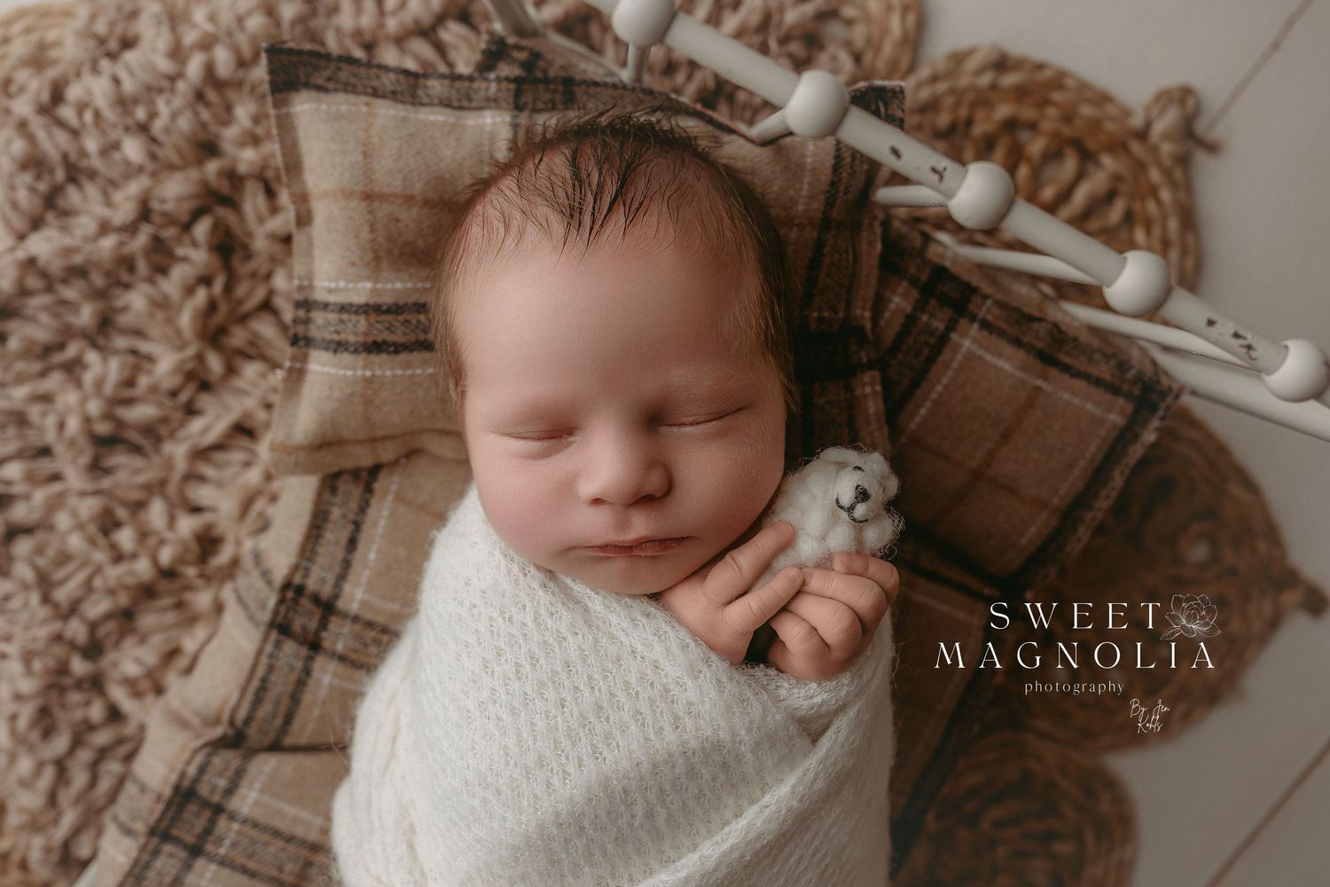 Cozy newborn portrait with cream knit wrap and delicate floral headband.