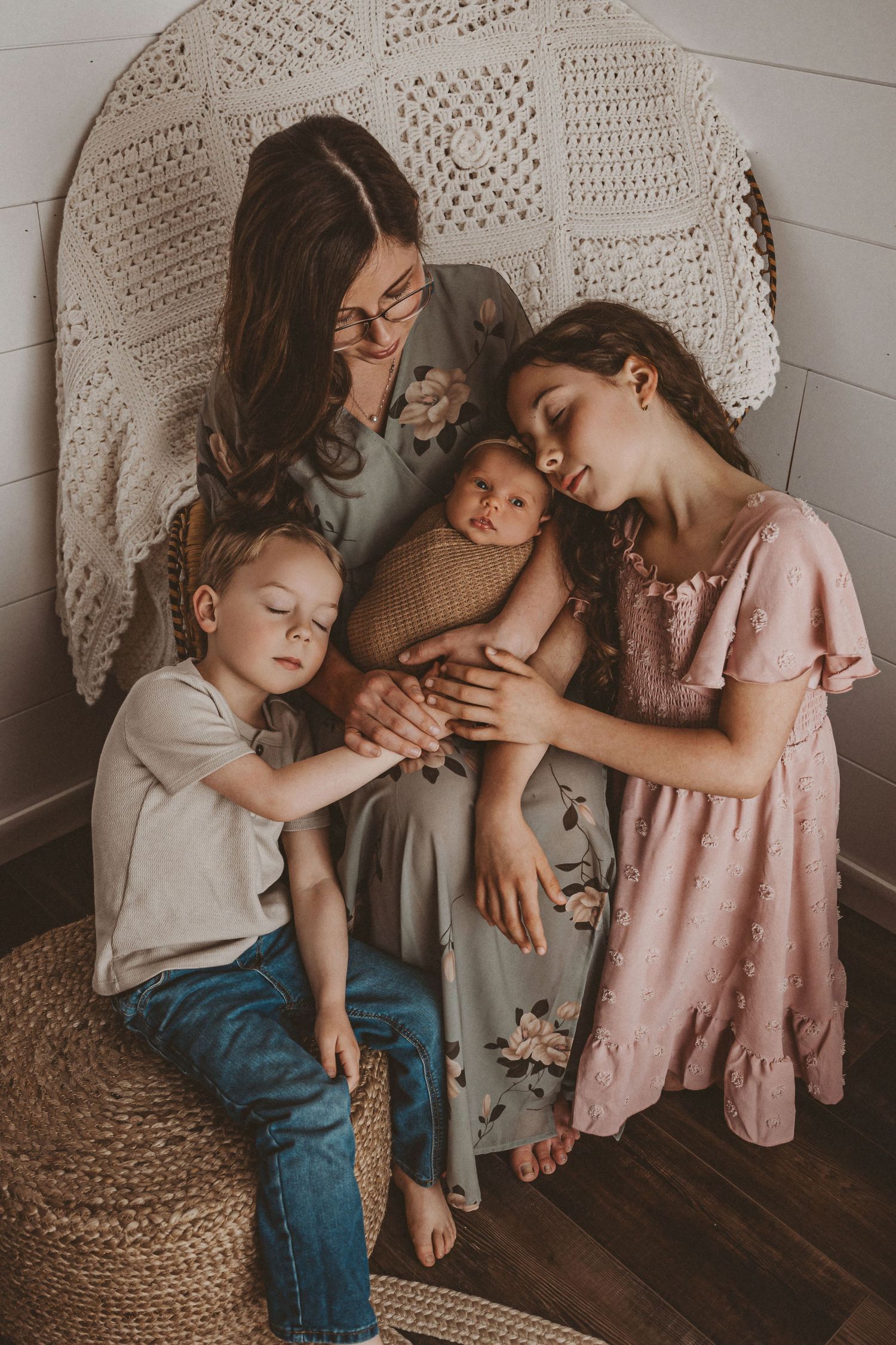 Sweet candid family moment captured on wooden floor with macrame backdrop.