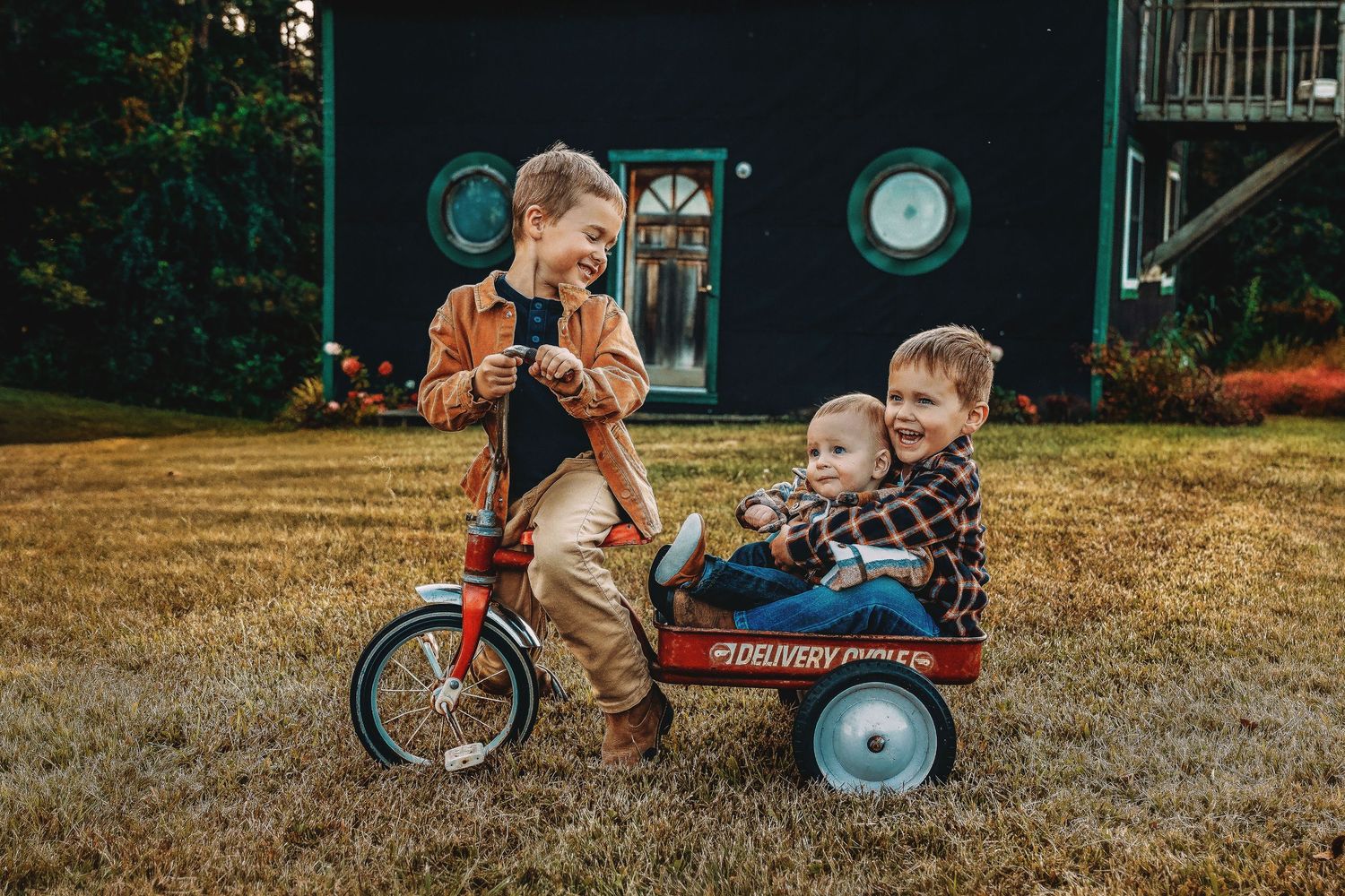 Children playing with a red wagon outdoors on a sunny afternoon.