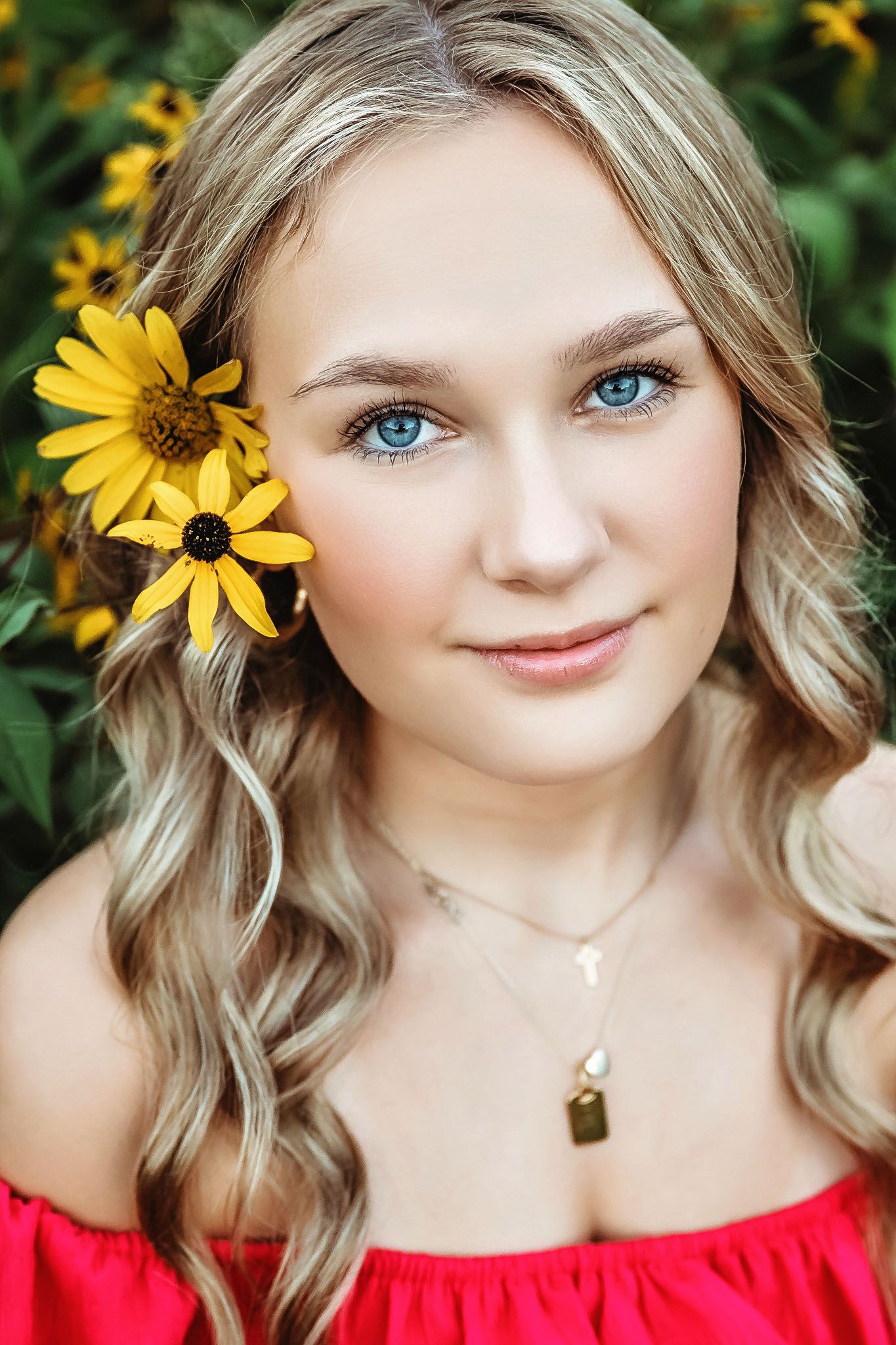 Portrait with yellow sunflowers and red top against natural garden background.