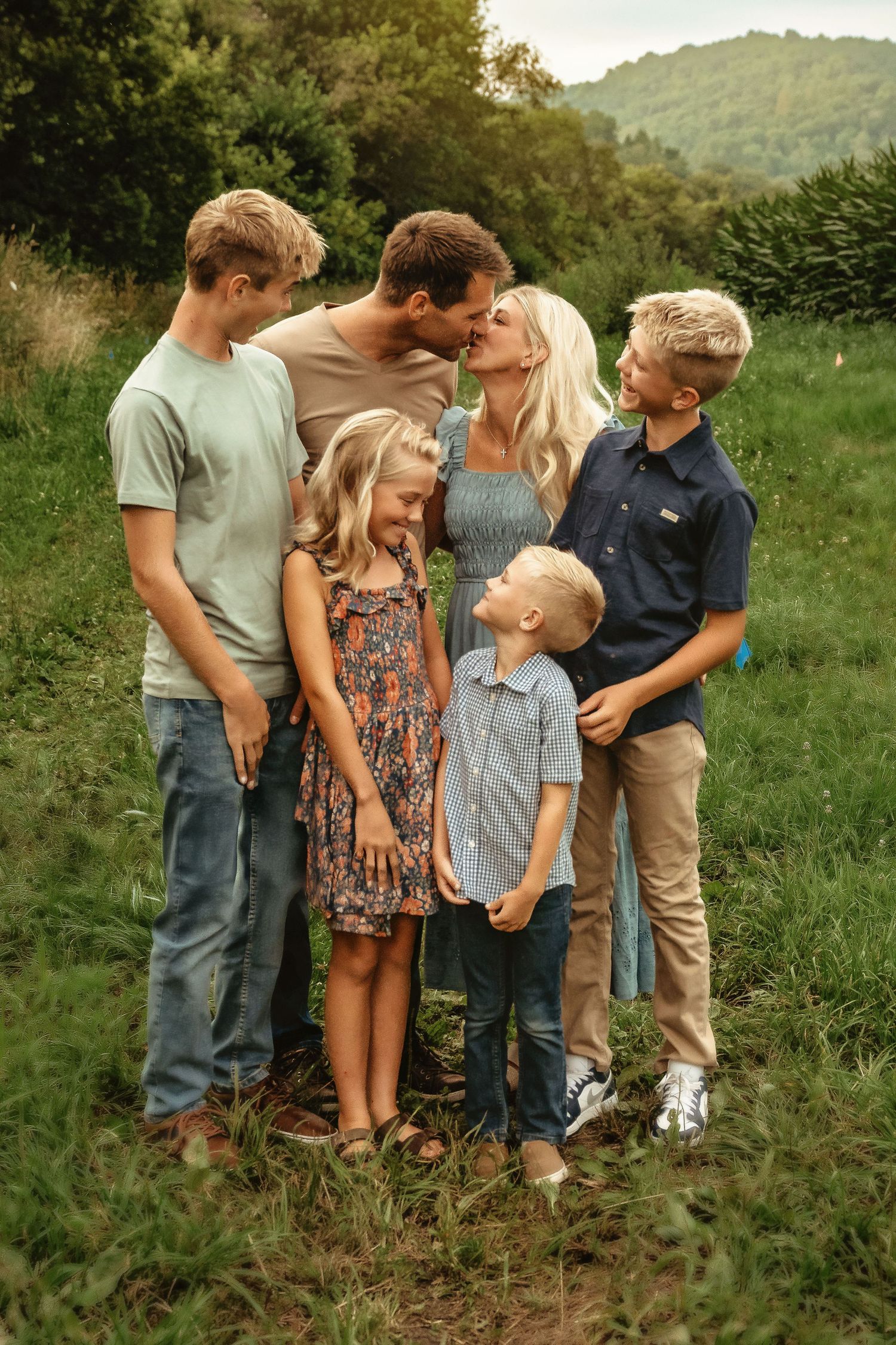 Group portrait in casual attire standing together on a grassy hillside.