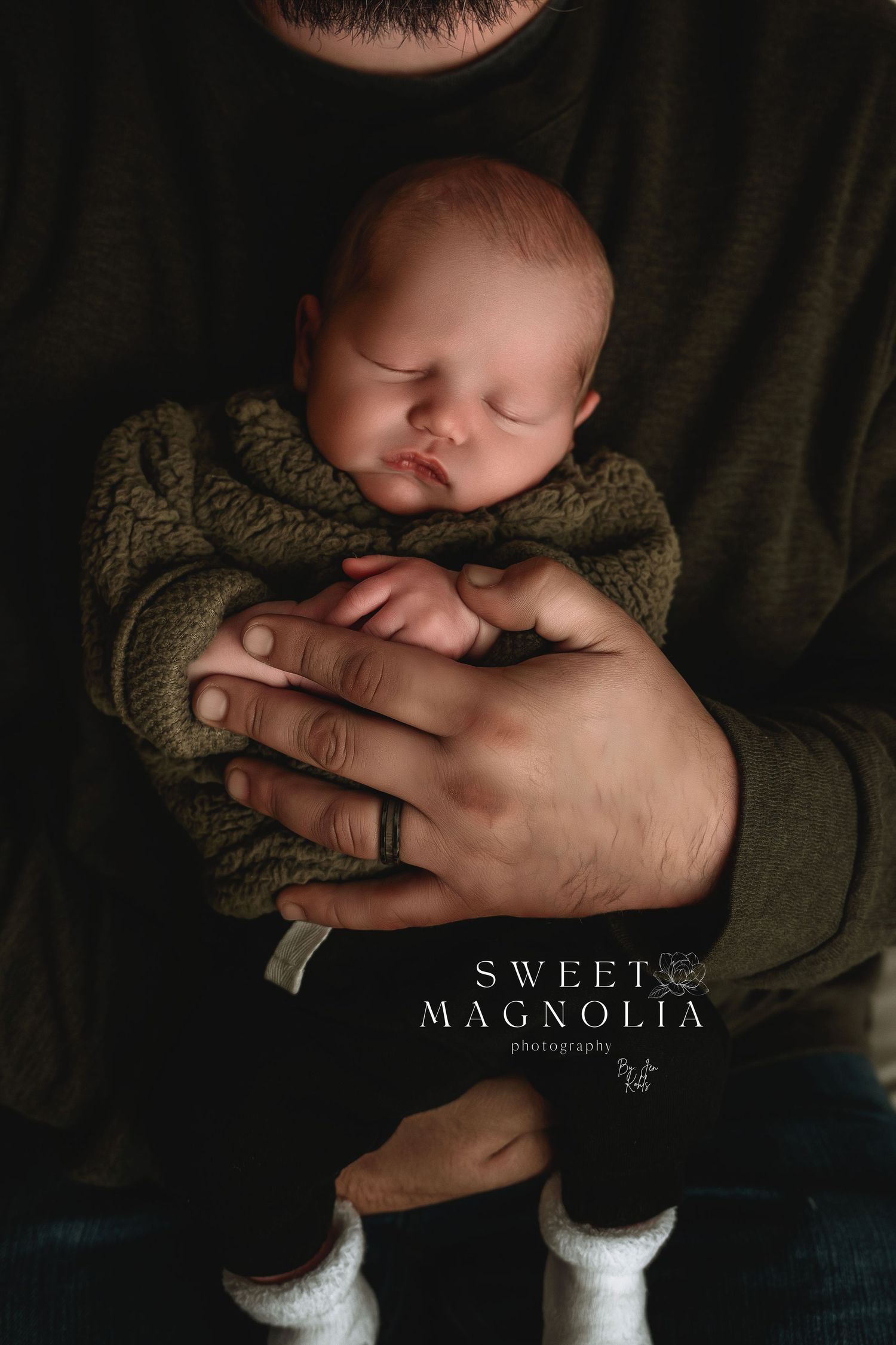Intimate dark newborn photography series with gentle hands cradling sleeping baby.