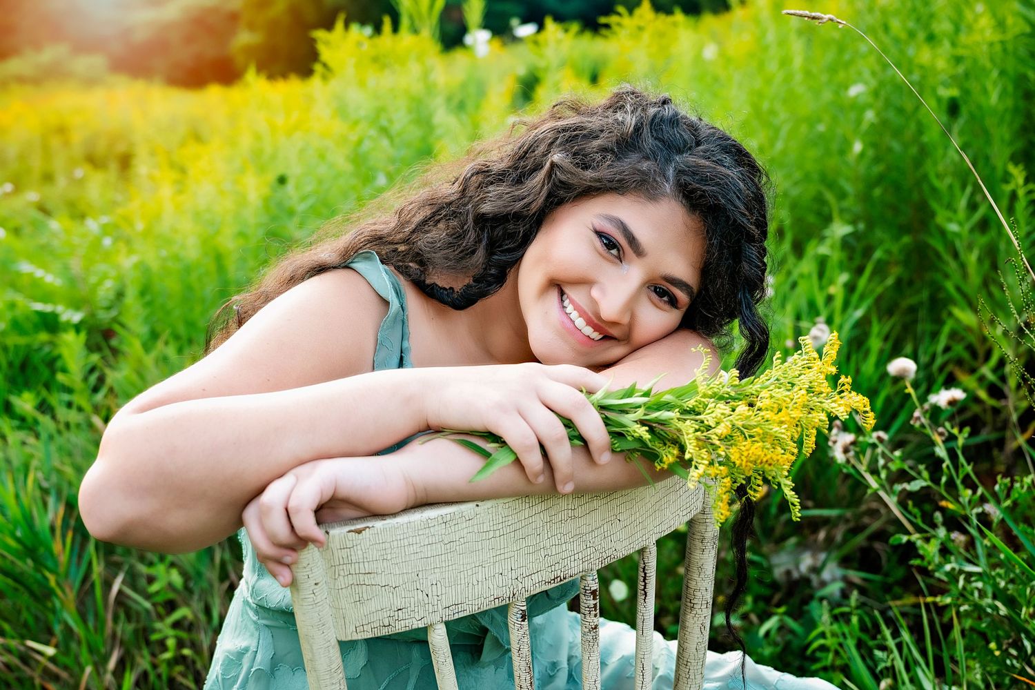 Senior portrait session in blooming yellow wildflower field during summer.