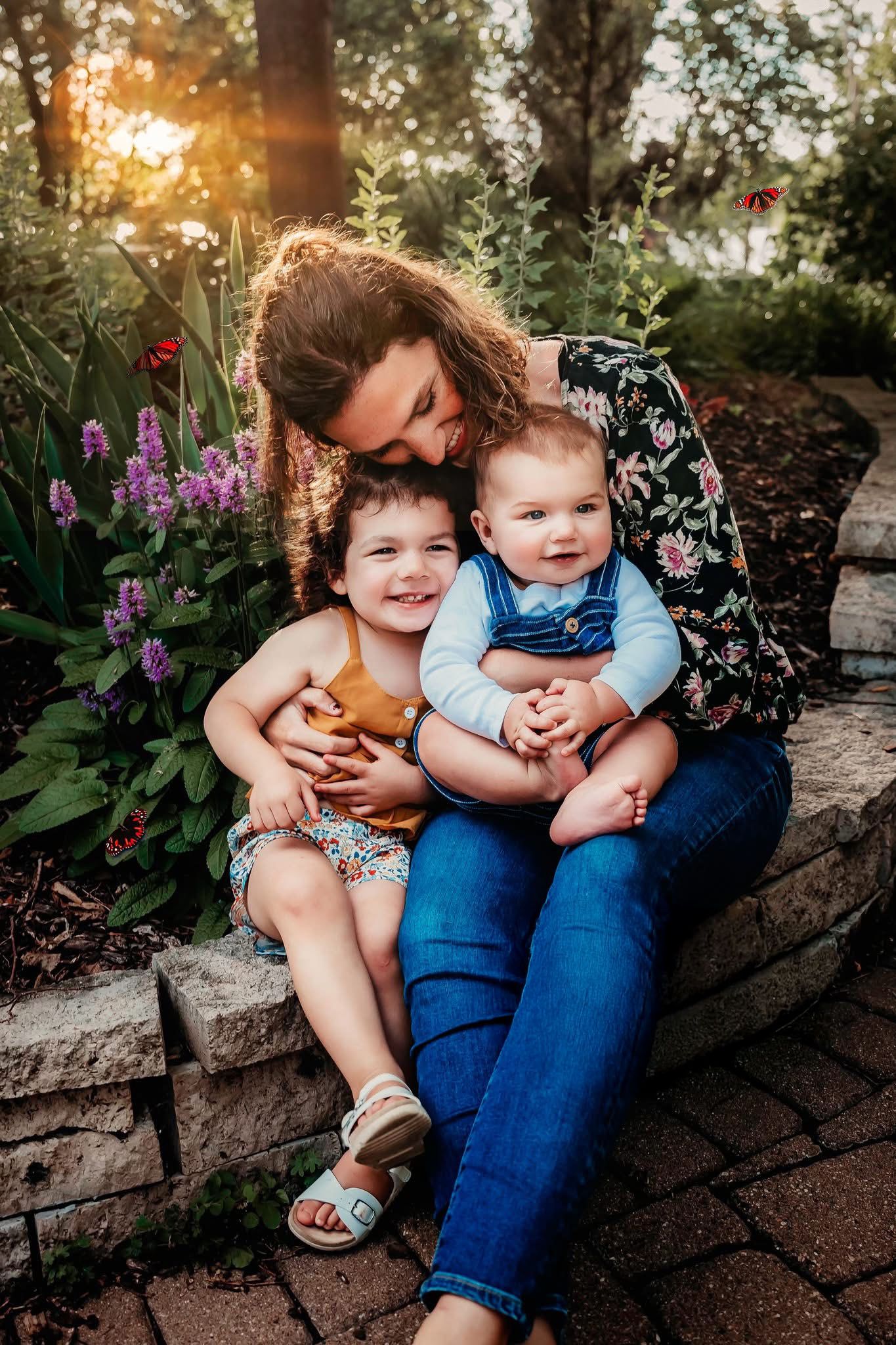A heartwarming outdoor portrait with children sitting on stone steps among blooming garden flowers at sunset.