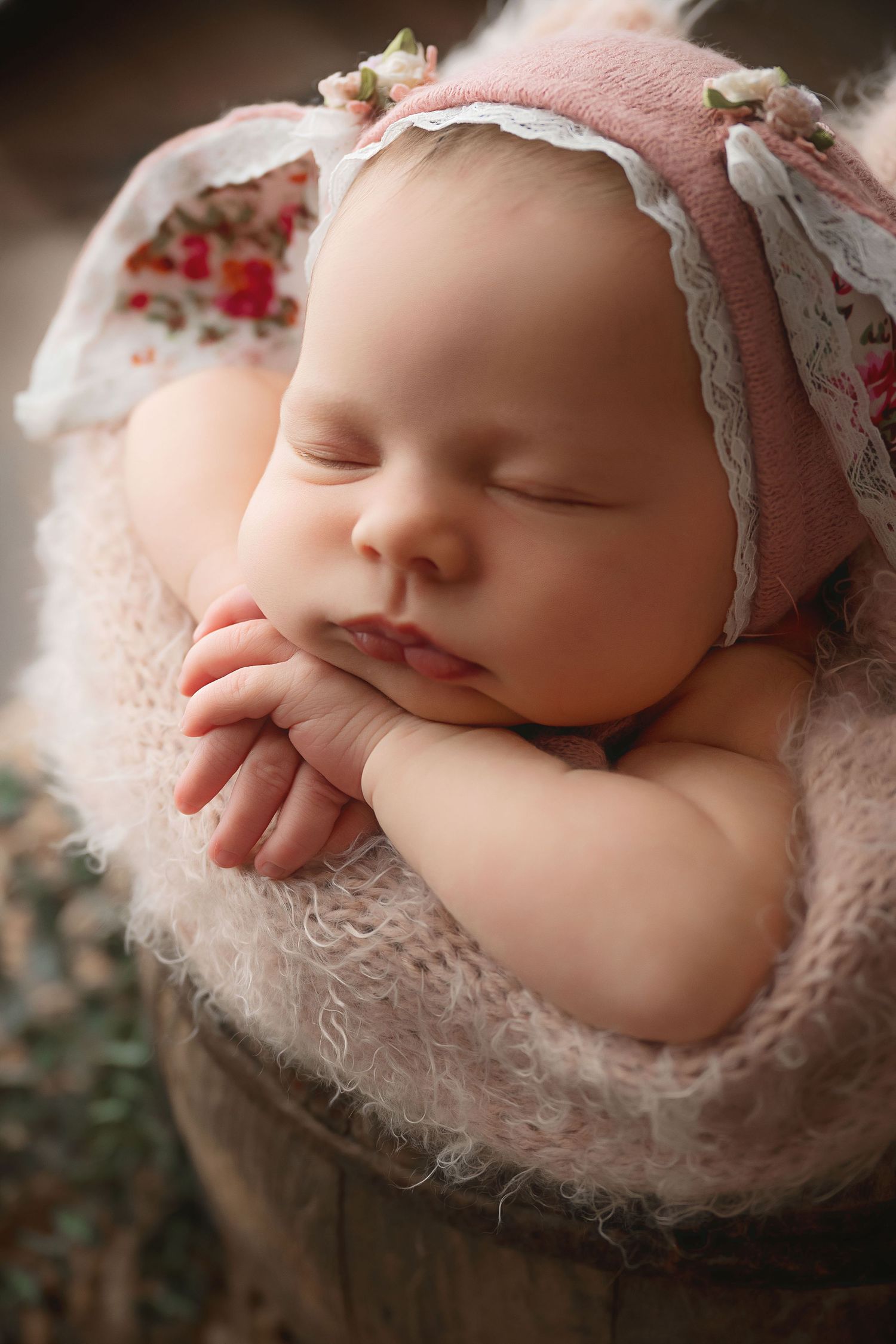 Peaceful newborn portrait with lace wrap and soft pink accessories.